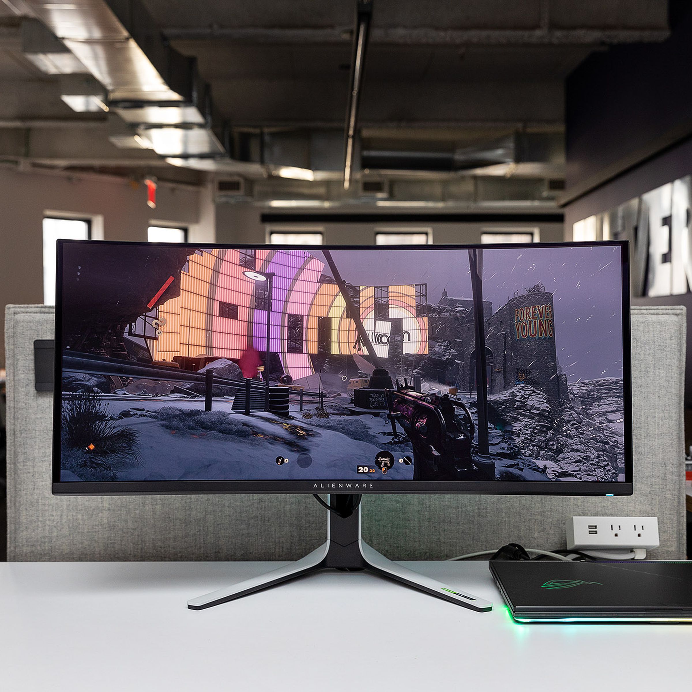 Alienware QD-OLED gaming monitor sitting on a white desk in a well-lit room displaying the game Deathloop.