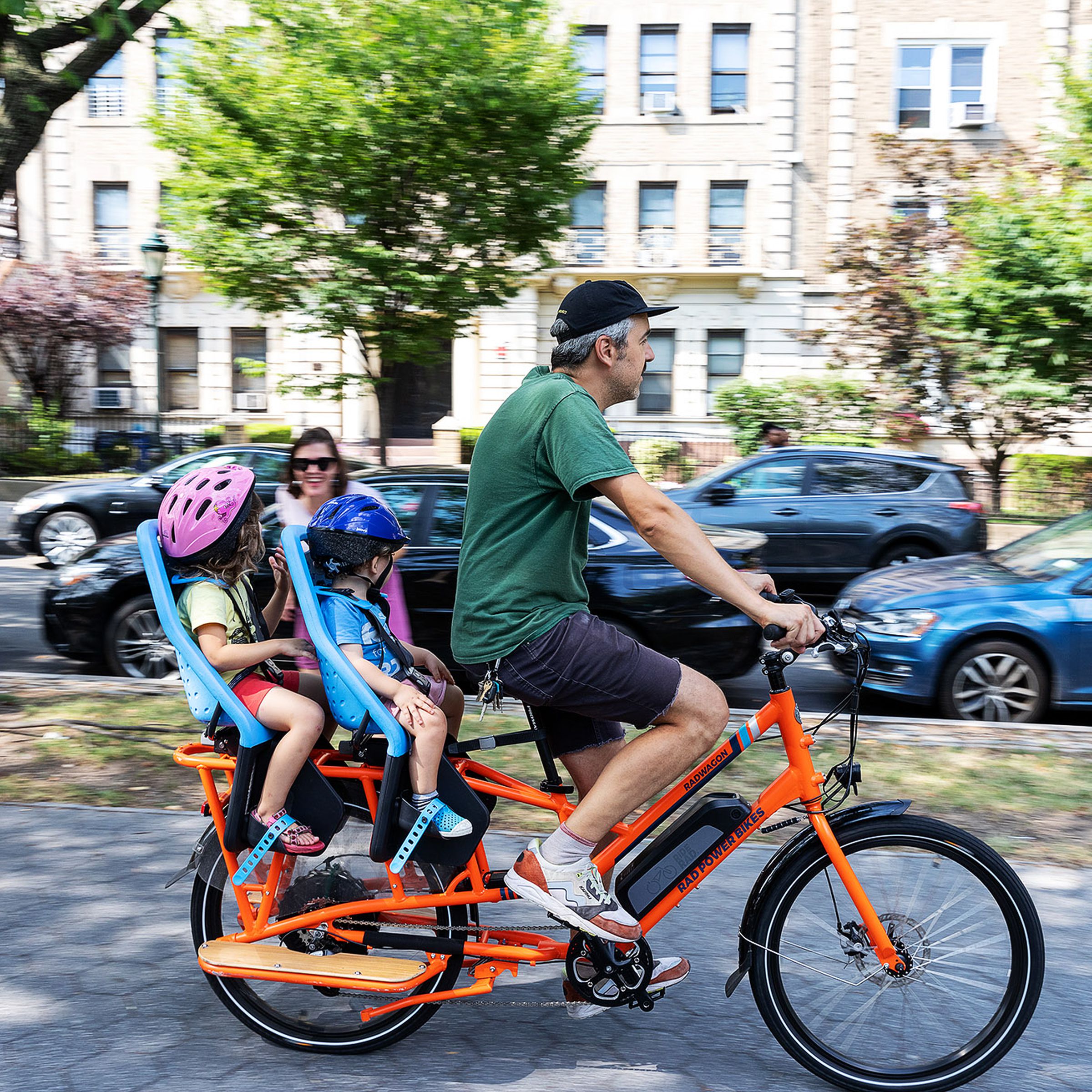 A dad riding an e-bike with two kids
