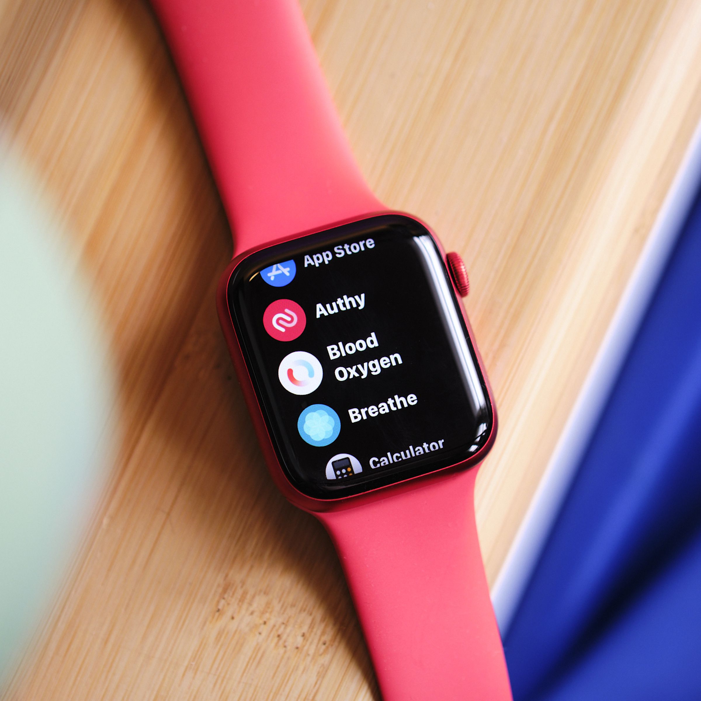 An Apple Watch with a red wristband sitting on a table, showing the blood oxygen app. 