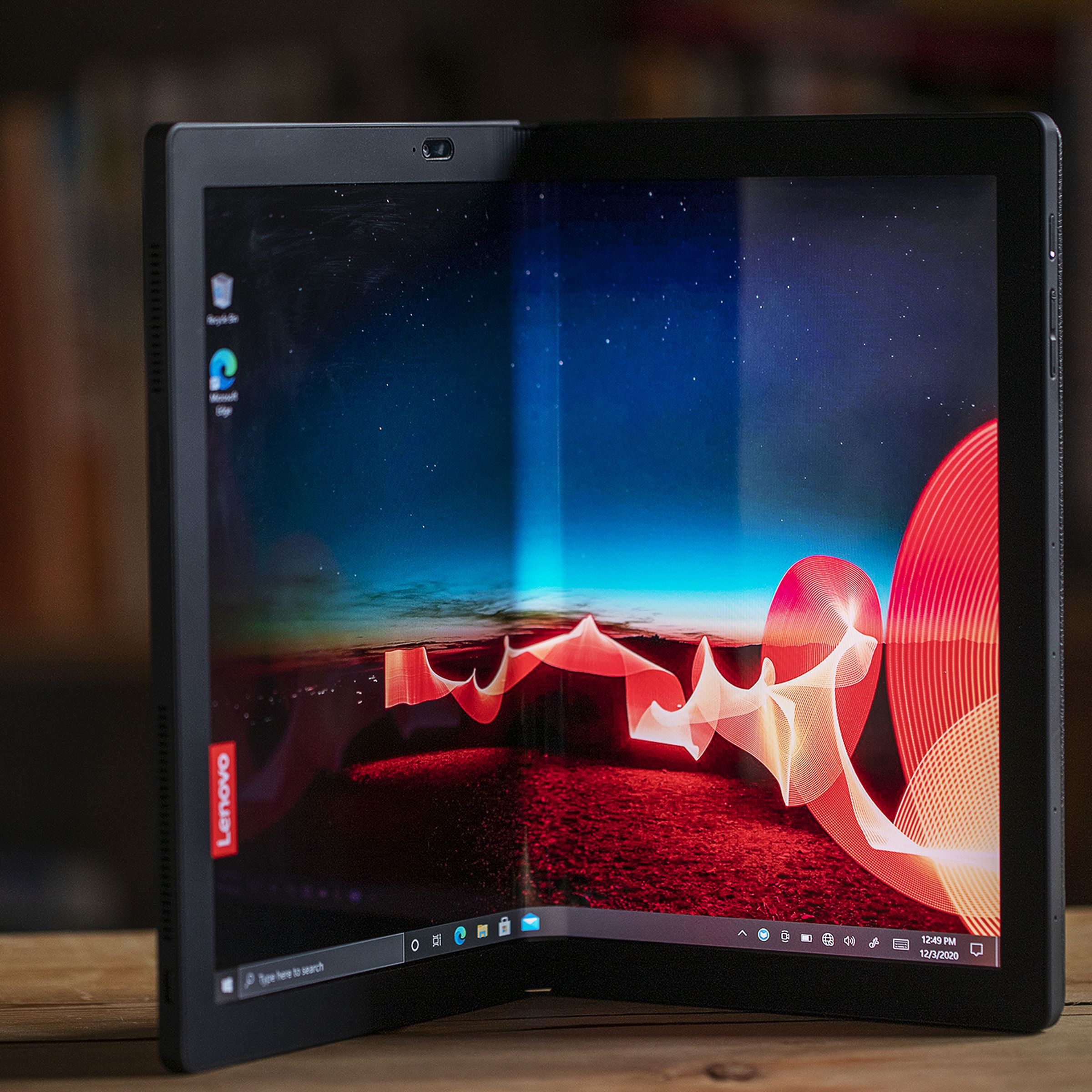 The Lenovo ThinkPad X1 Fold stands on a table in book mode.
