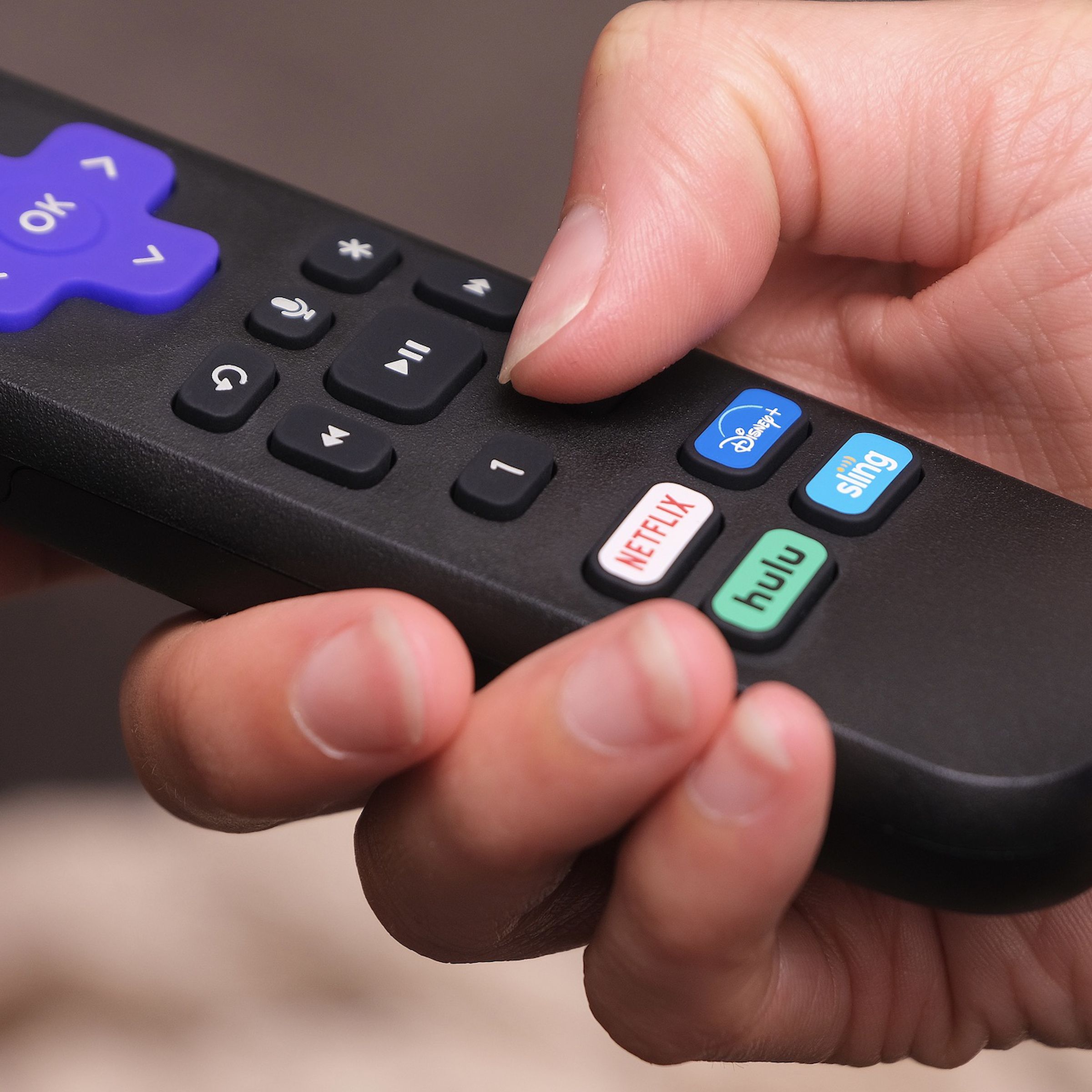 A photo of a Roku remote in a person’s hand.
