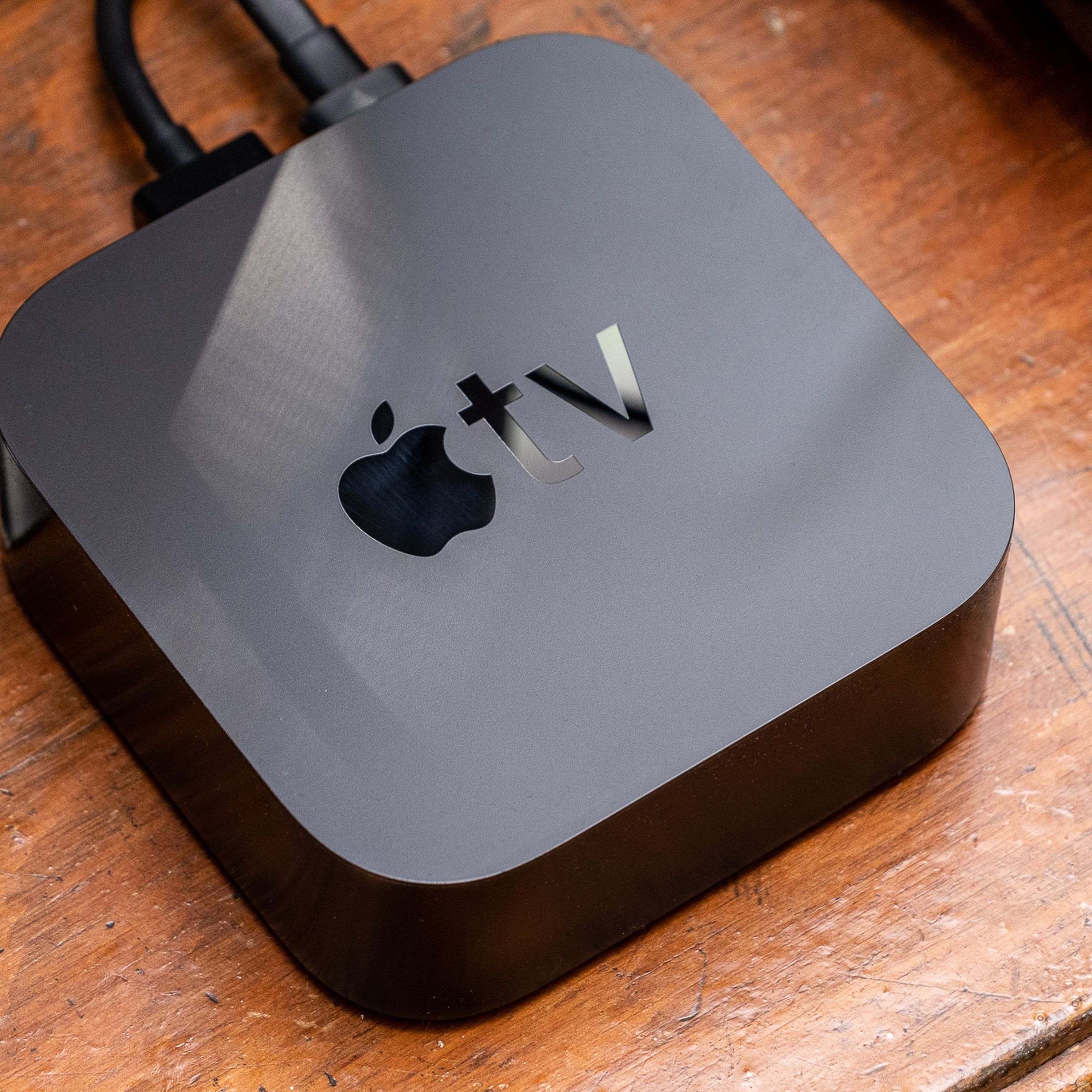 A photo of the Apple TV 4K set on top of a brown wooden surface.