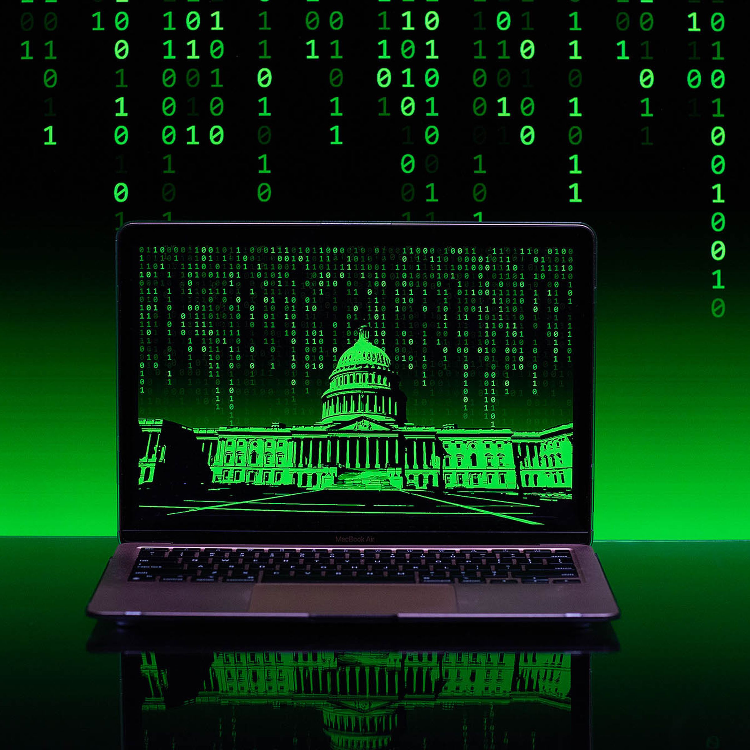 A matrix of green binary code flows down in the background of a laptop computer with a green hued image of the US capitol building