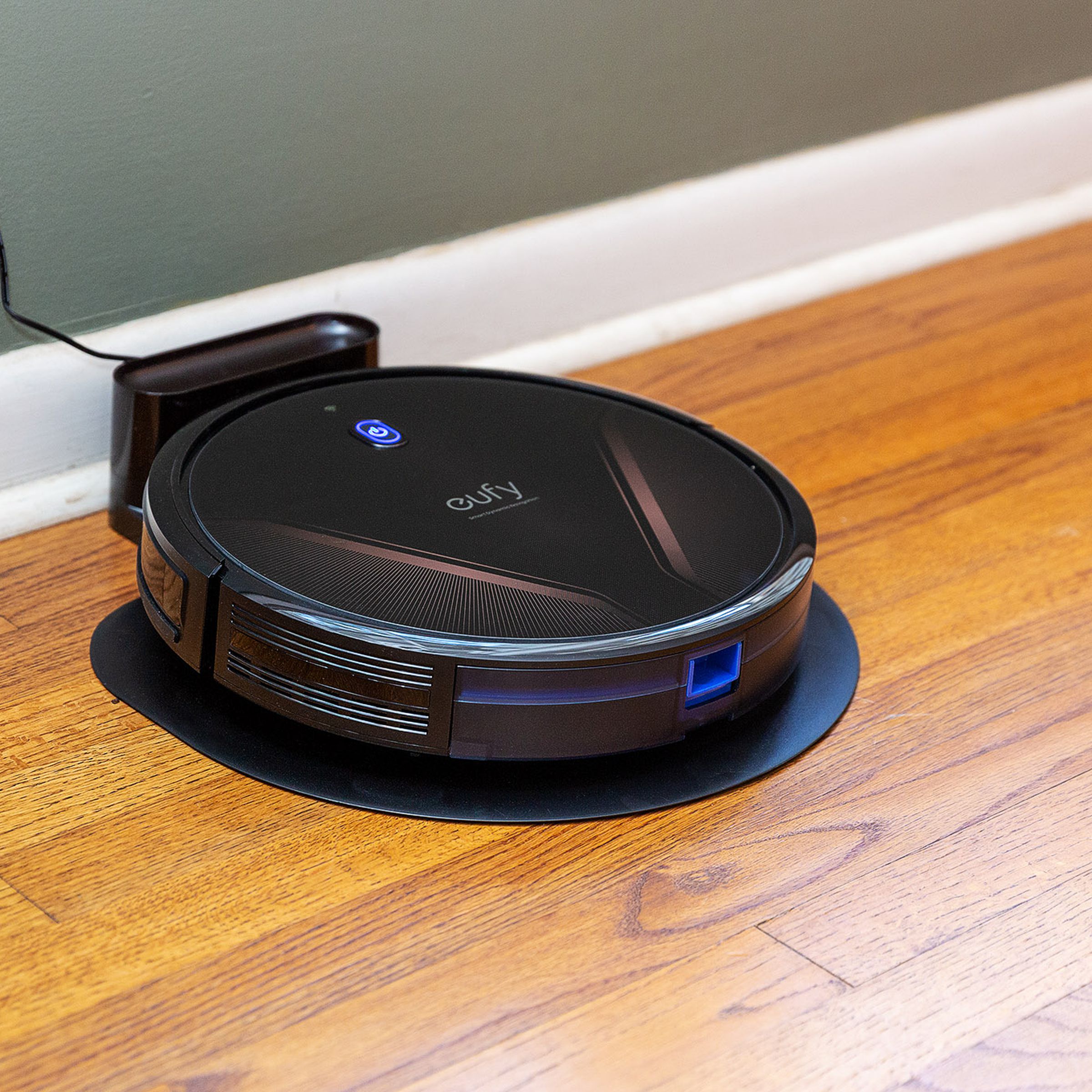 Eufy’s G20 Hybrid plugged into the wall resting on a hardwood floor.