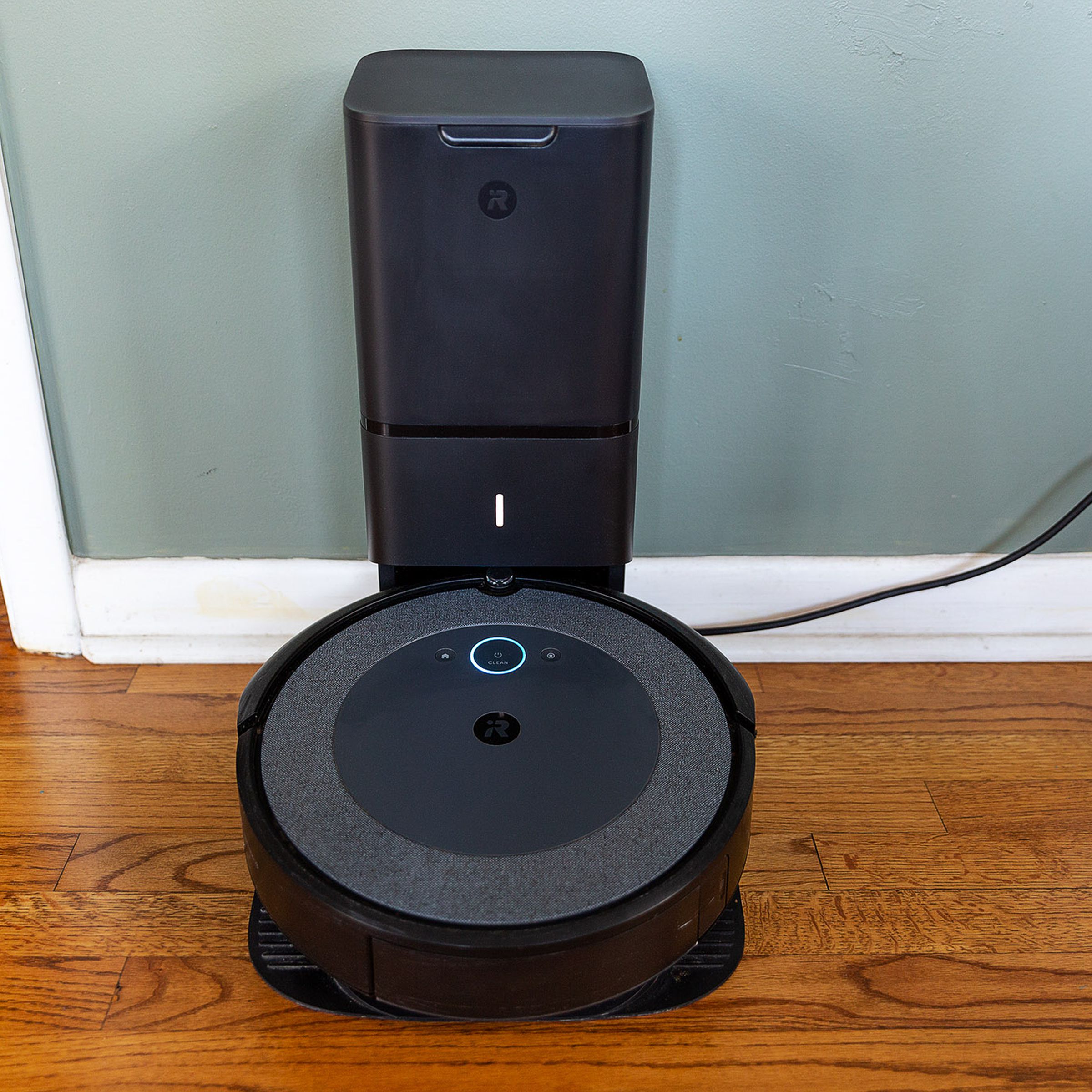 A centered image of the iRobot Roomba i4 Evo resting on its auto-empty dock against a wall.
