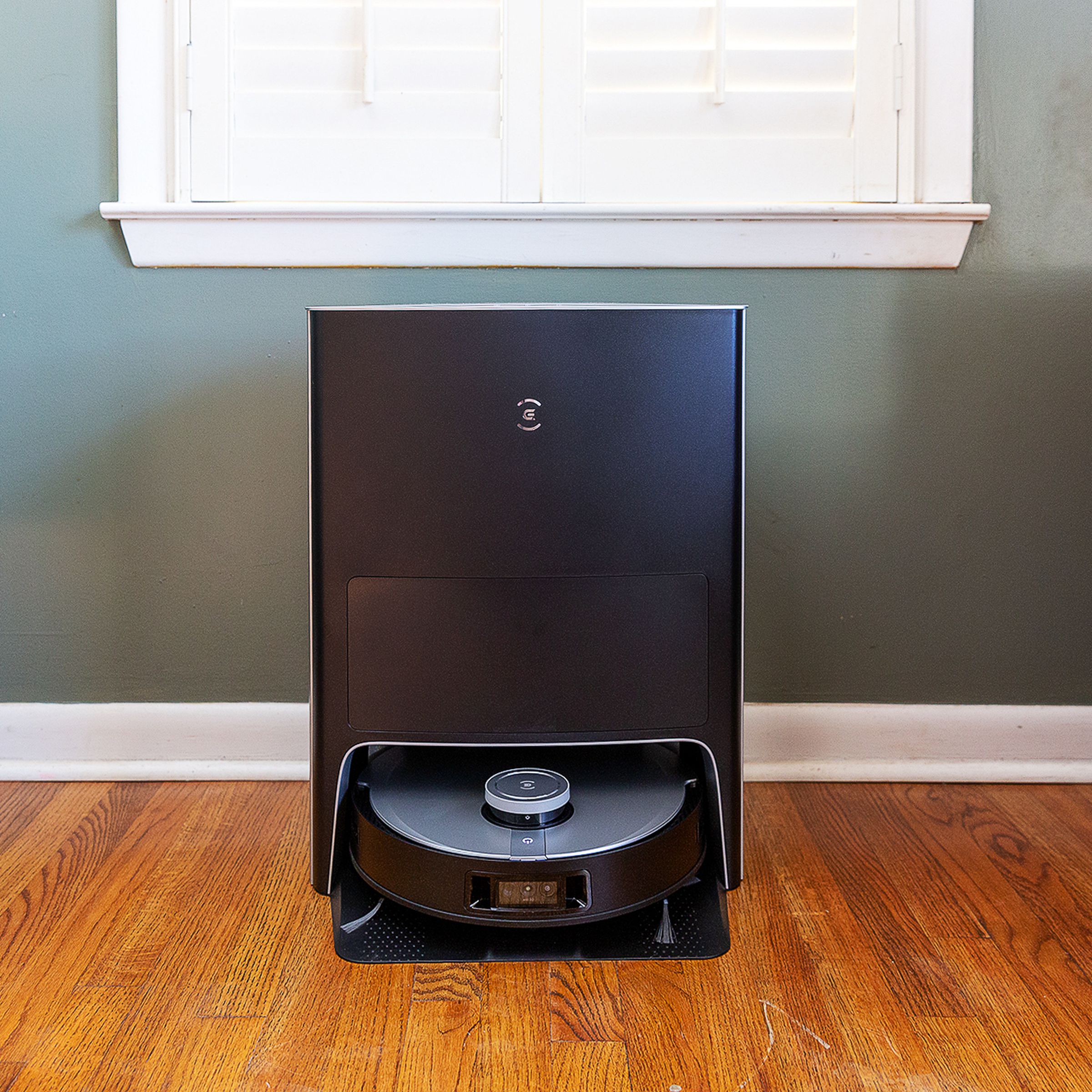 An Ecovacs Deebot X1 Omni robot vacuum, docked in its self-cleaning station in a living room.