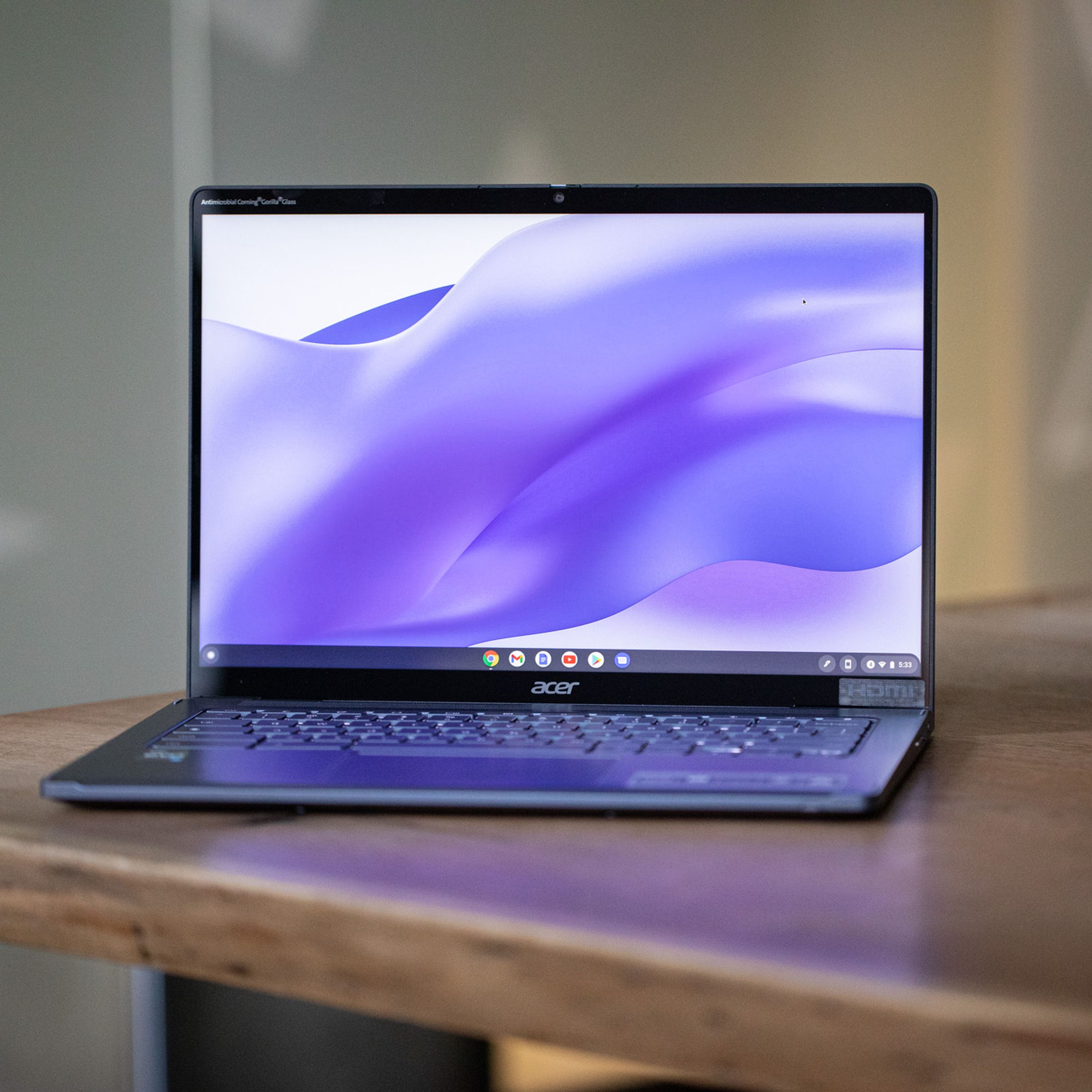 The Acer Chromebook Spin 714 open on a table. The screen displays a purple painted background.