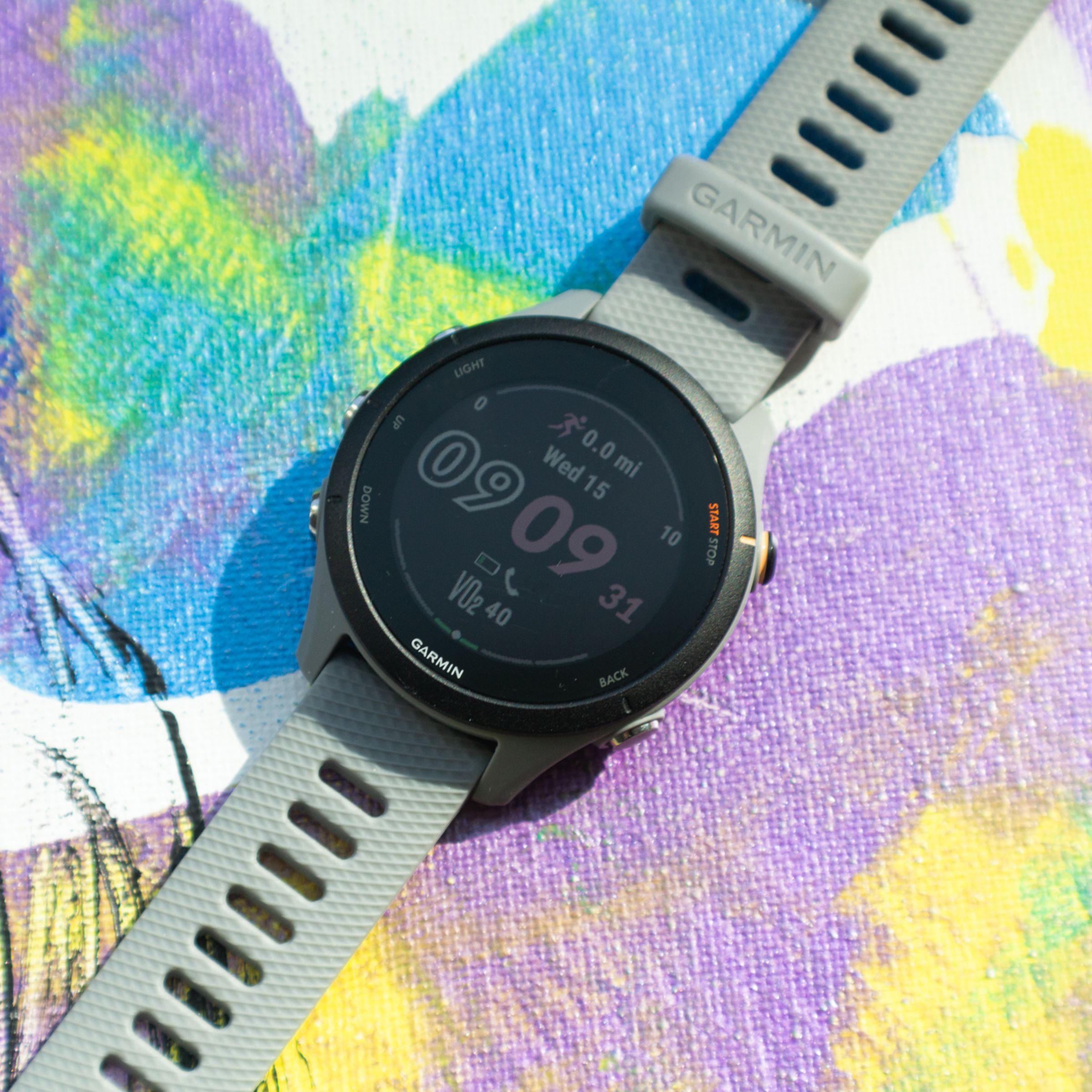 Garmin Forerunner 255S smartwatch on a colorful background