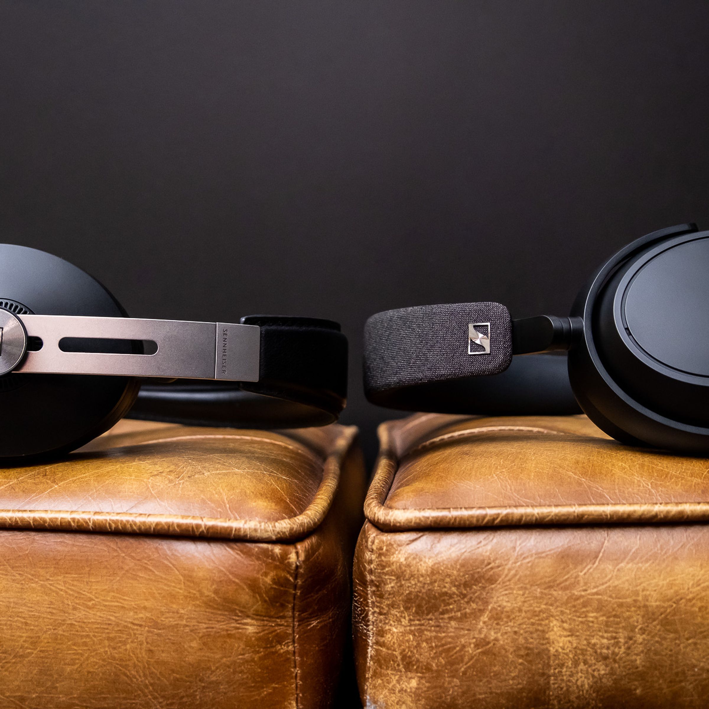 The Sennheiser Momentum 3 and Sennheiser Momentum 4 headphones facing each other while lying on a couch.