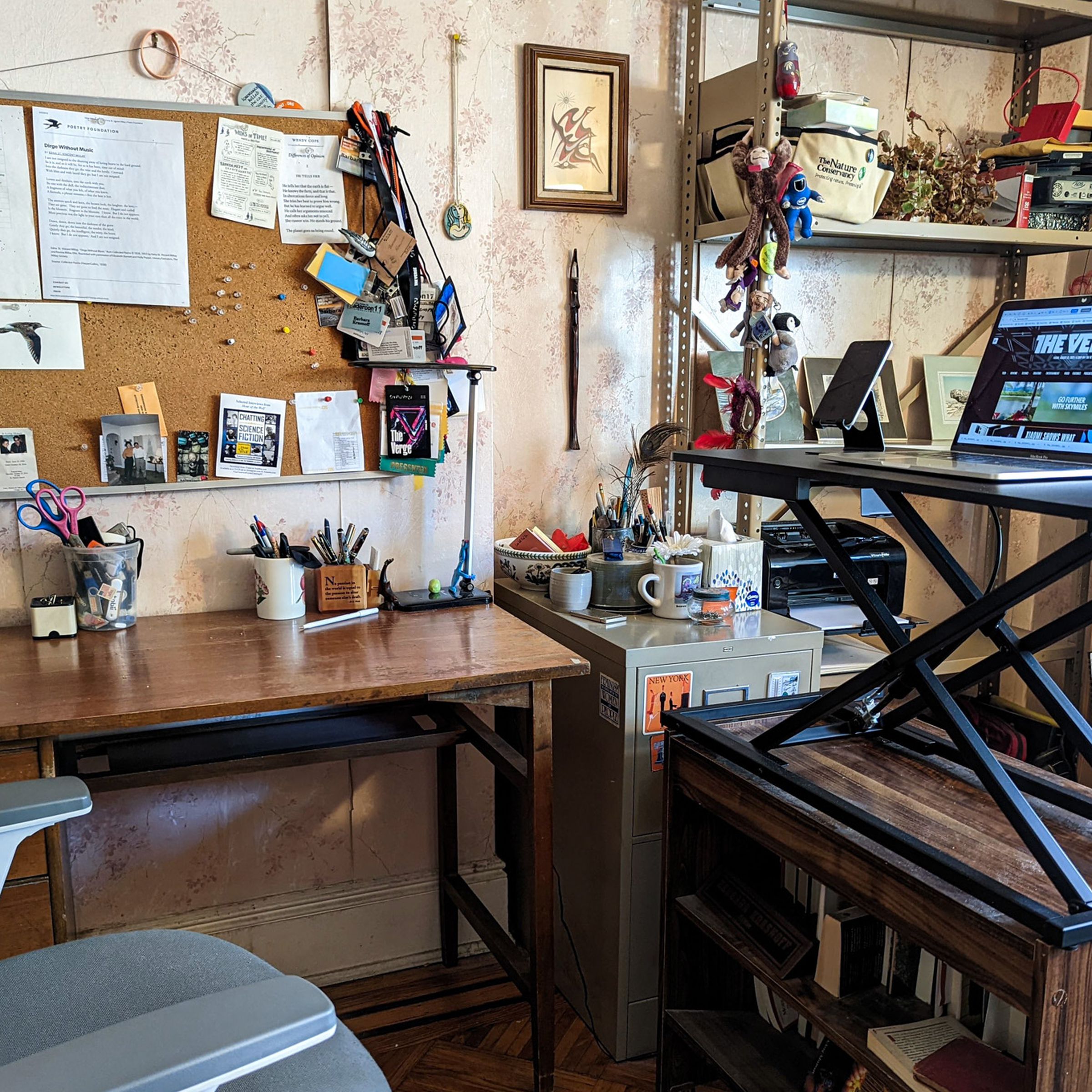 A messy office with a stand for a standing desk