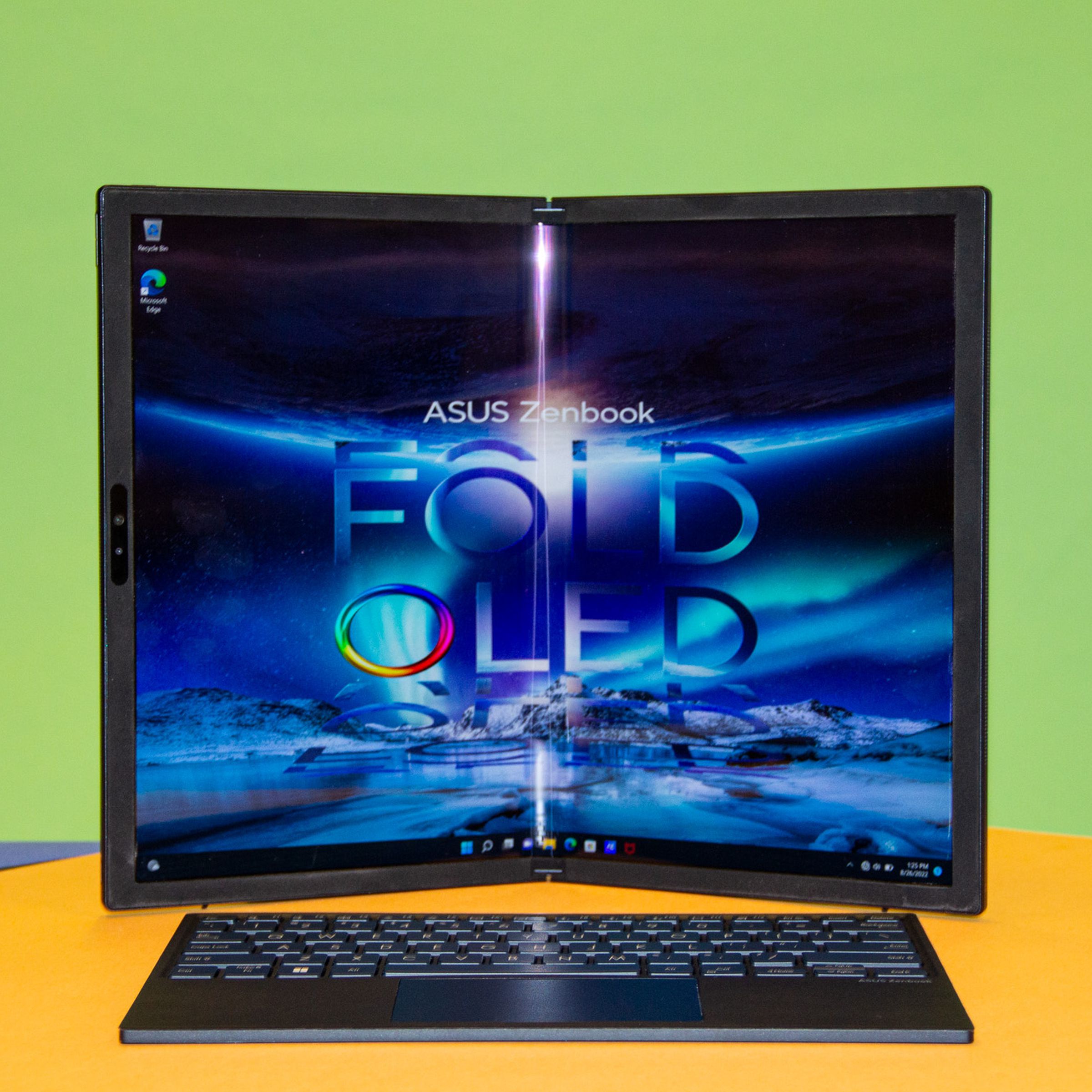 The Zenbook 17 Fold OLED in book mode with the keyboard in front. The screen displays the Asus Zenbook Fold OLED logo on a blue background.