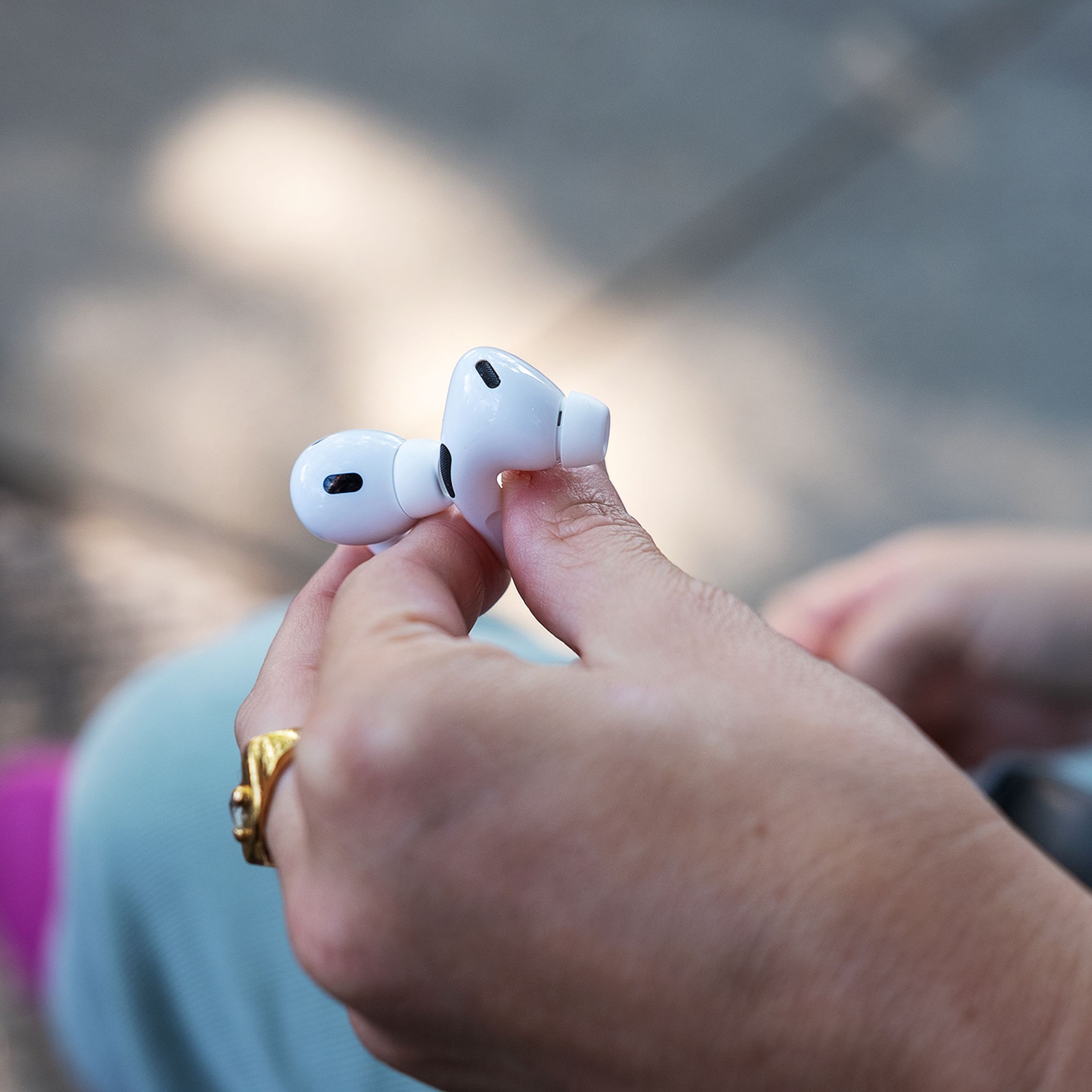 A person holds two AirPods Pro earbuds in their hand.