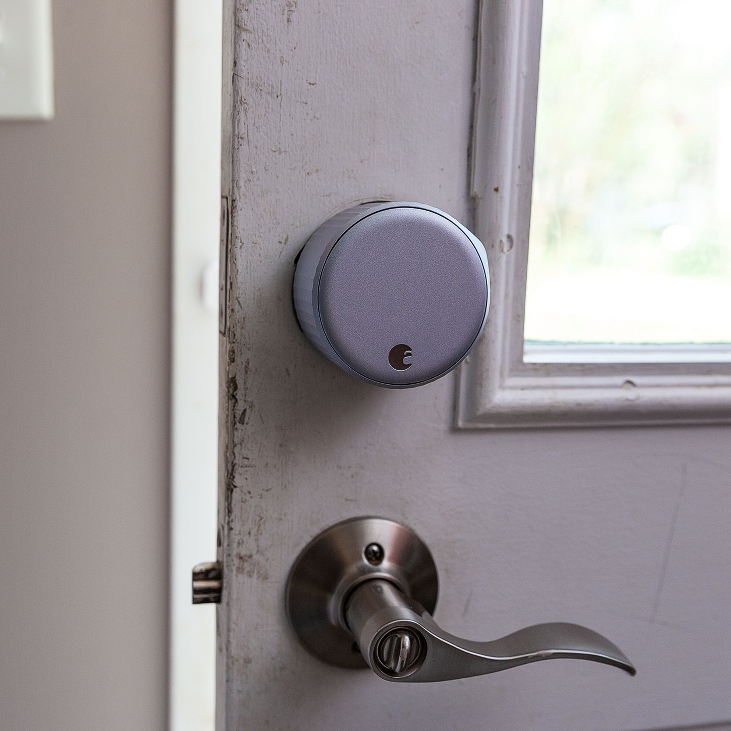 A large silver door lock on a door above a lever handle