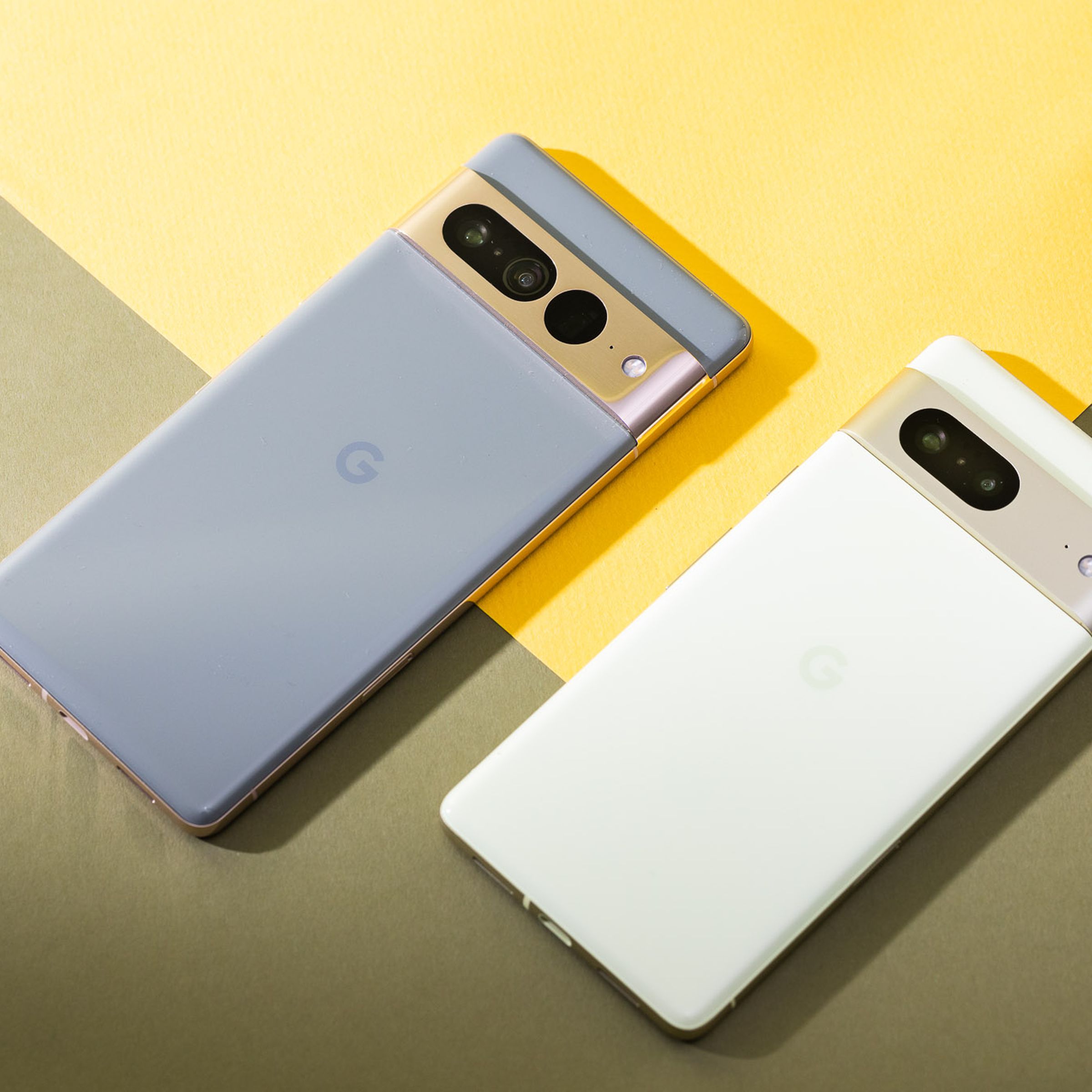 Pixel 7 Pro in hazel and Pixel 7 in lemongrass laying down on a flat surface with back panels facing up.