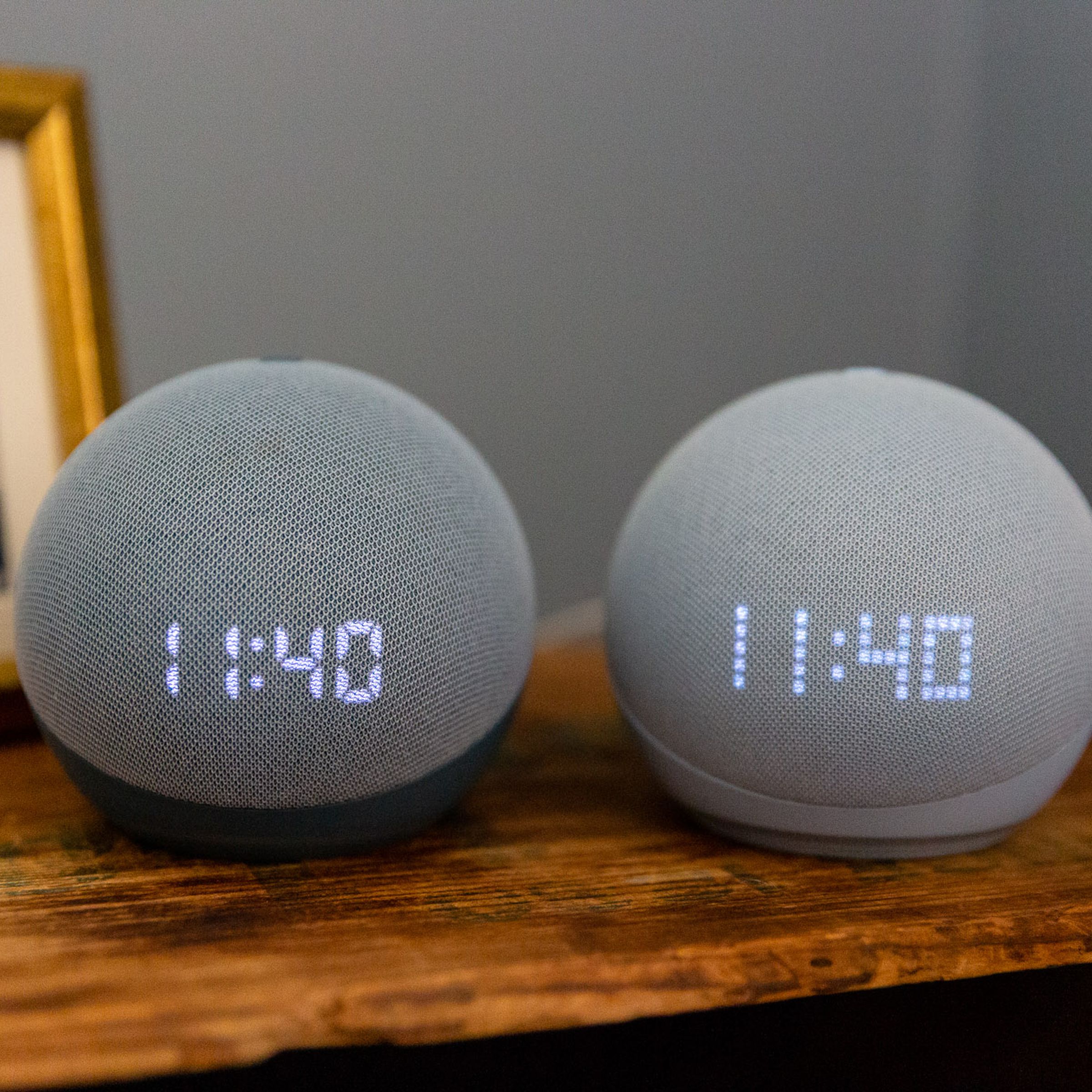 Two Echo Dot with Clock speakers on a bedside table.