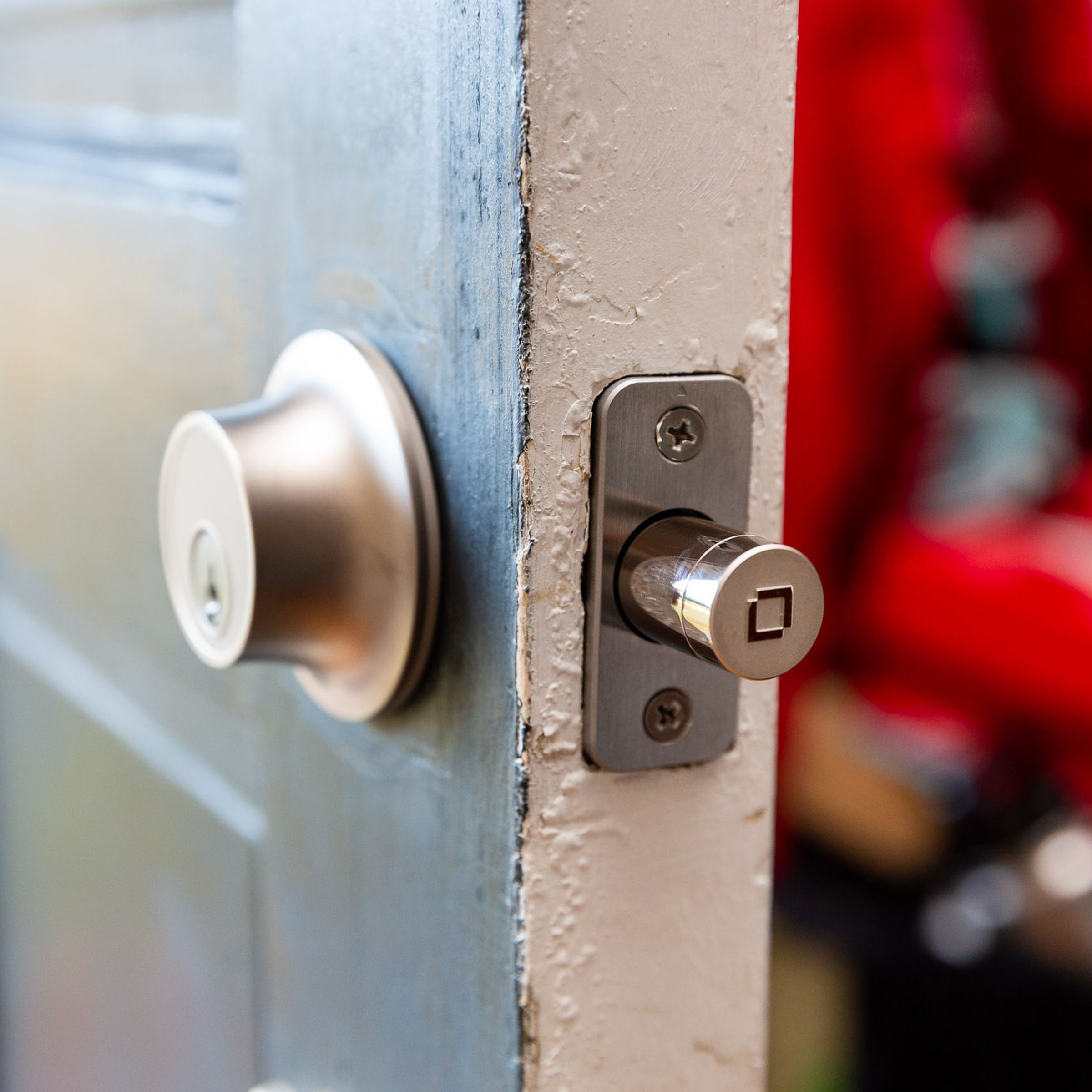 Photo of the Level Lock Plus in satin nickel installed on a door. The door is ajar, and the deadbolt is extended.