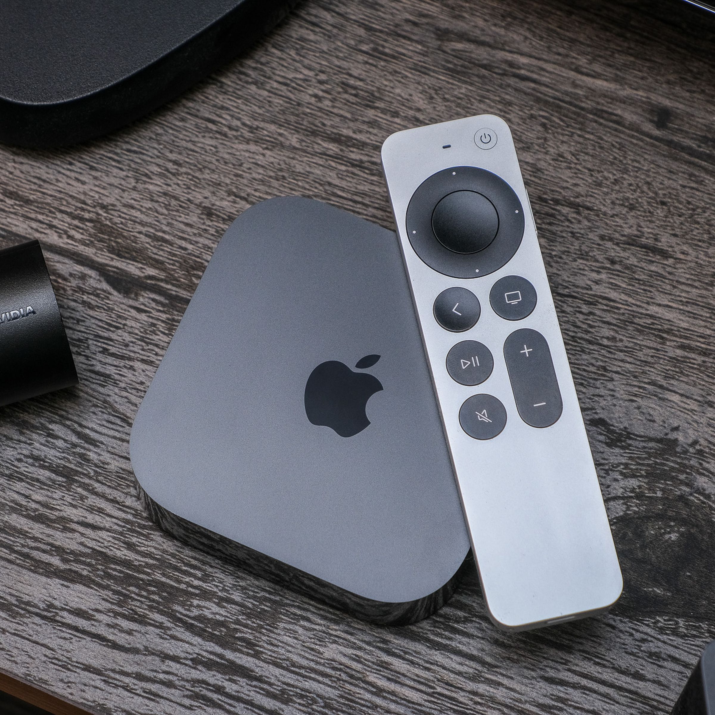A photo of the third-gen Apple TV 4K on a TV stand surrounded by competing products from Amazon, Roku, and Nvidia.