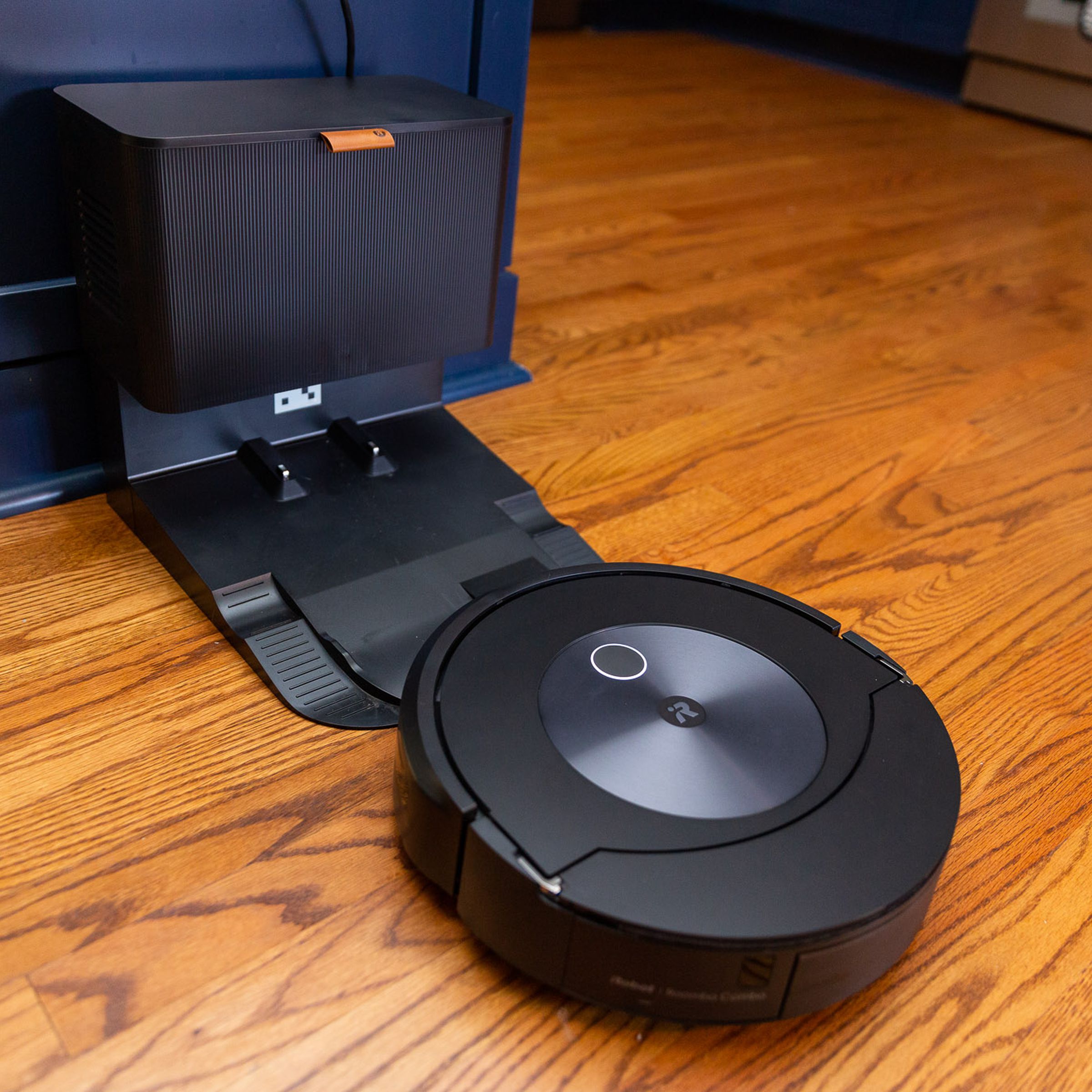 Photo of the Roomba Combo J7 approaching its auto-empty base. The base is about the size of a small kitchen trash can.