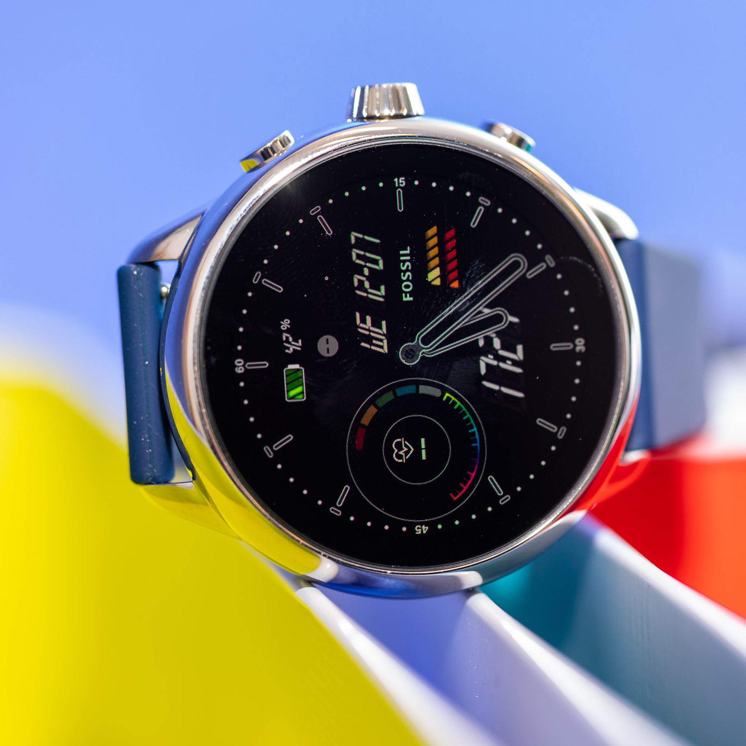 Close-up of the Fossil Gen 6 Wellness Edition’s watchface while it sits atop colorful bins