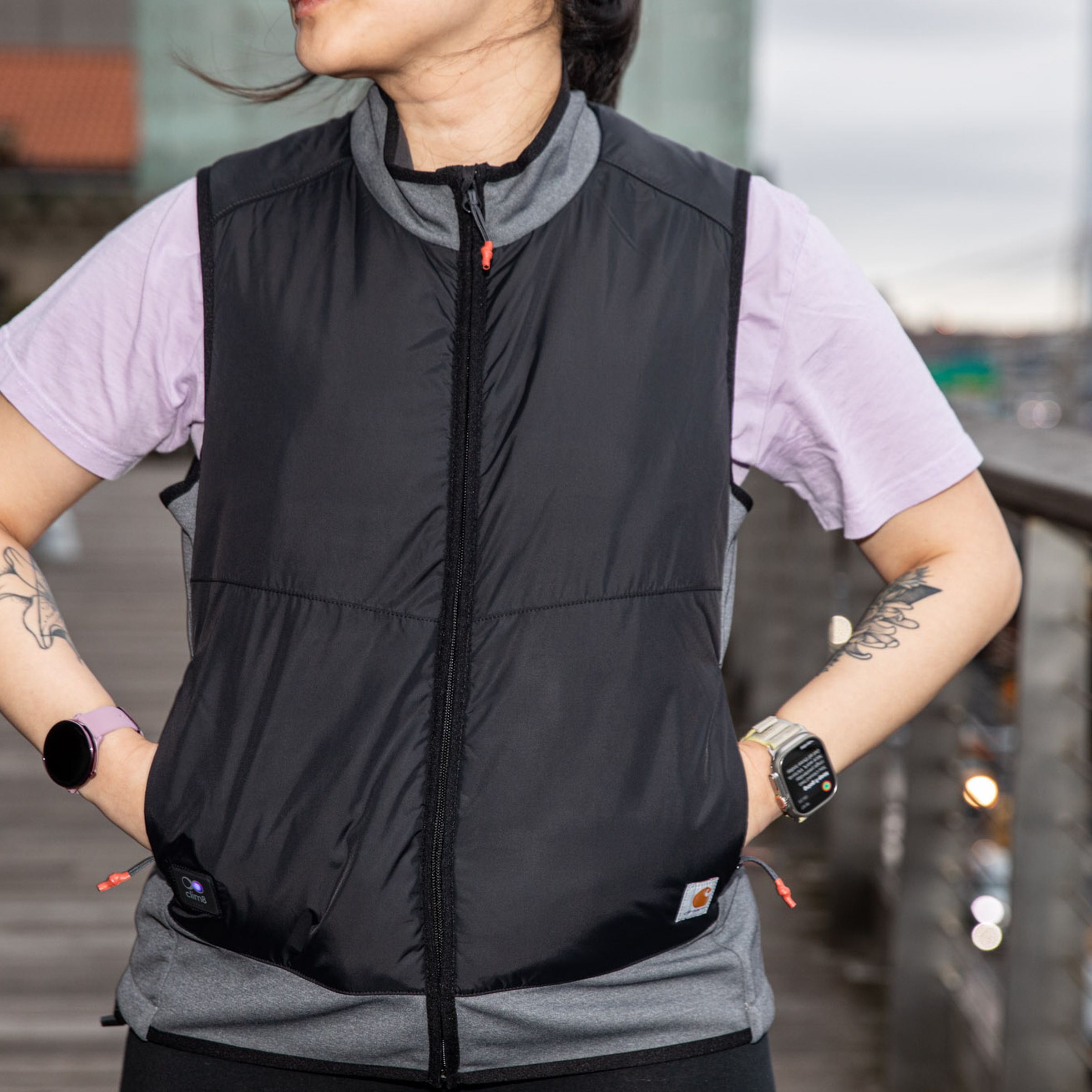 Woman wearing Carhartt X-1 Smart Heated Vest on top of a short-sleeve T-shirt with hands in pockets.