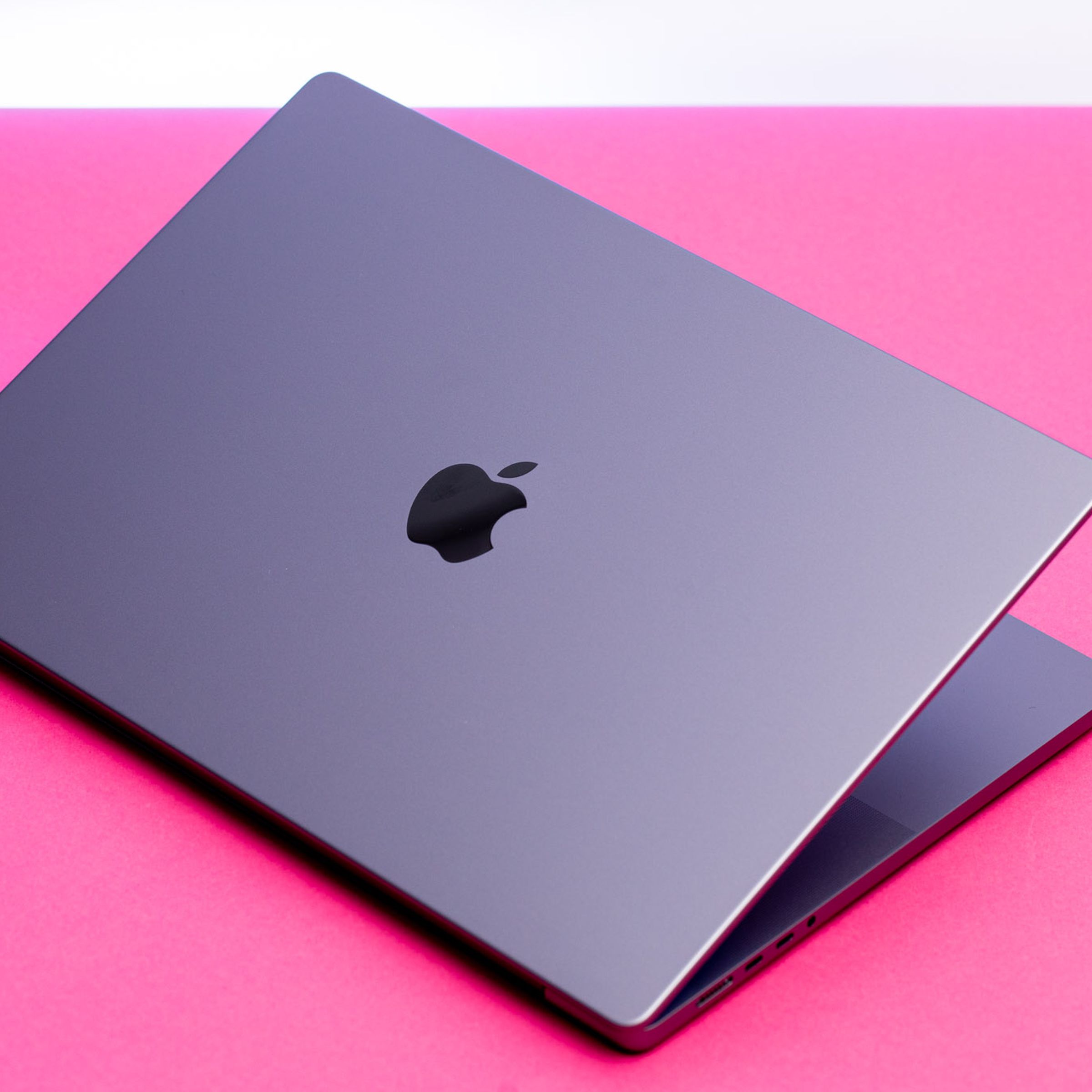 The MacBook Pro 16 half open seen from above on a pink table.
