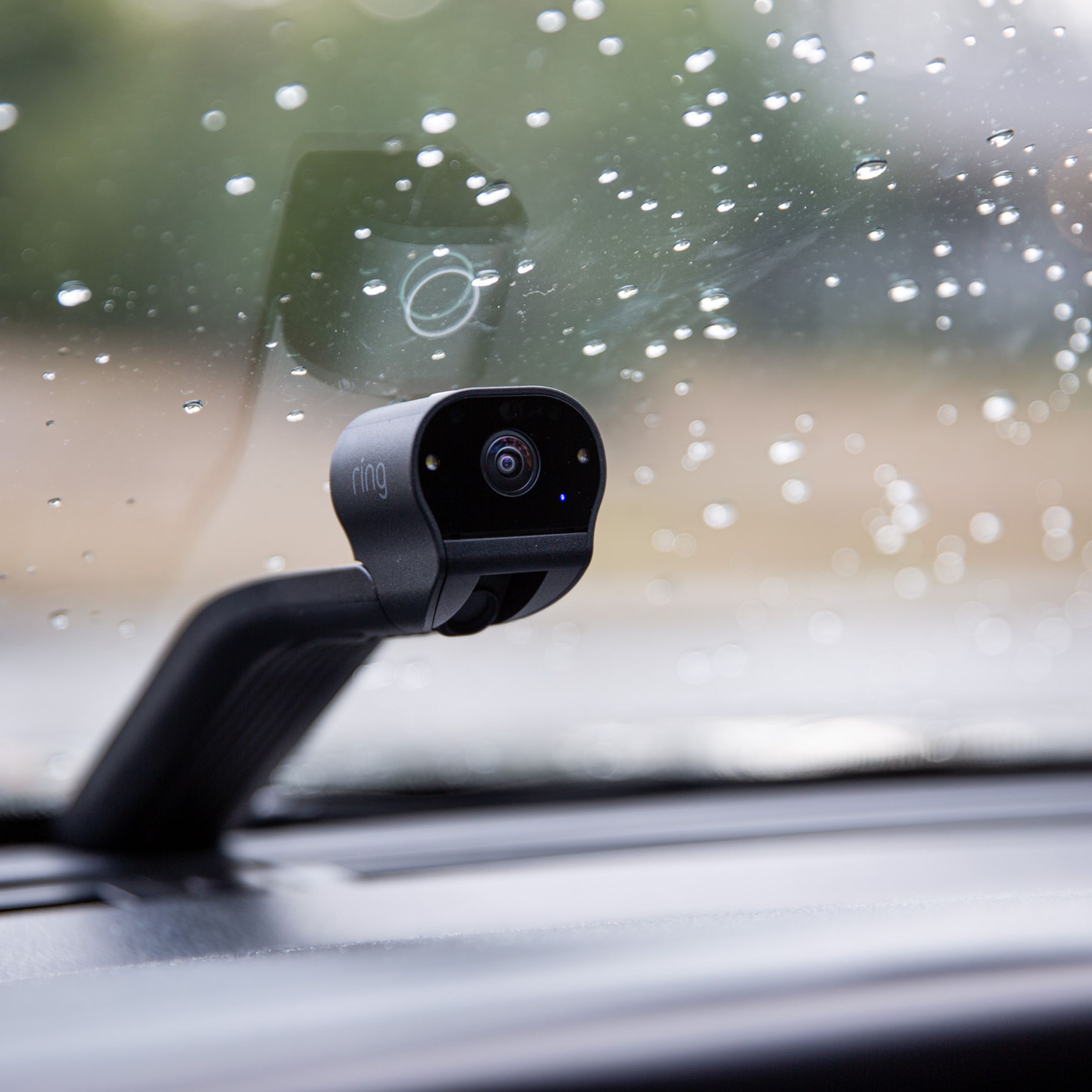 A small camera on top of a long black stand fitted onto a car windshield.