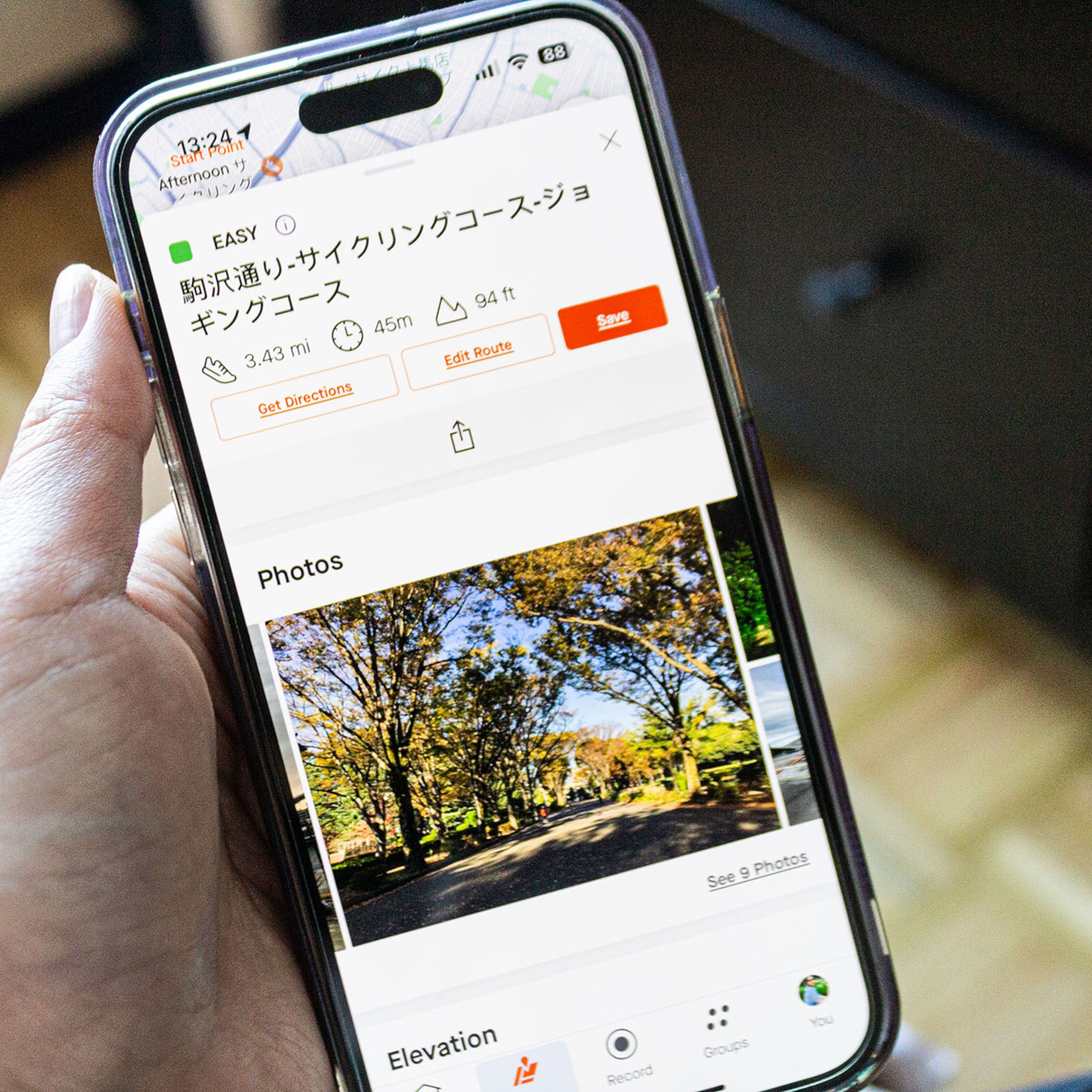 Person holding iPhone showing the new Strava Recommended Routes photo feature with a route in Tokyo.