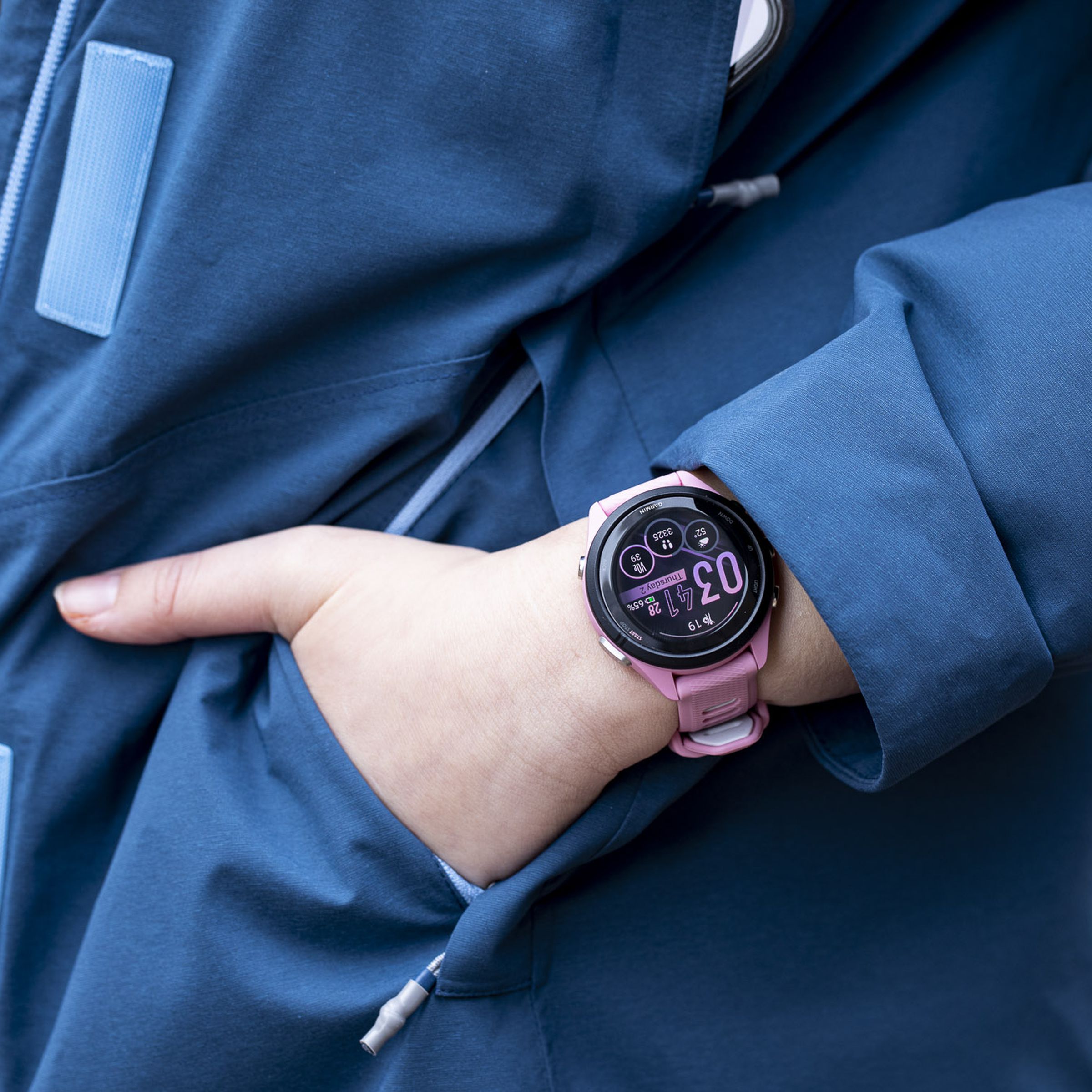 Close-up of the Garmin Forerunner 265S on the wrist of a person putting their hand into a jacket pocket.