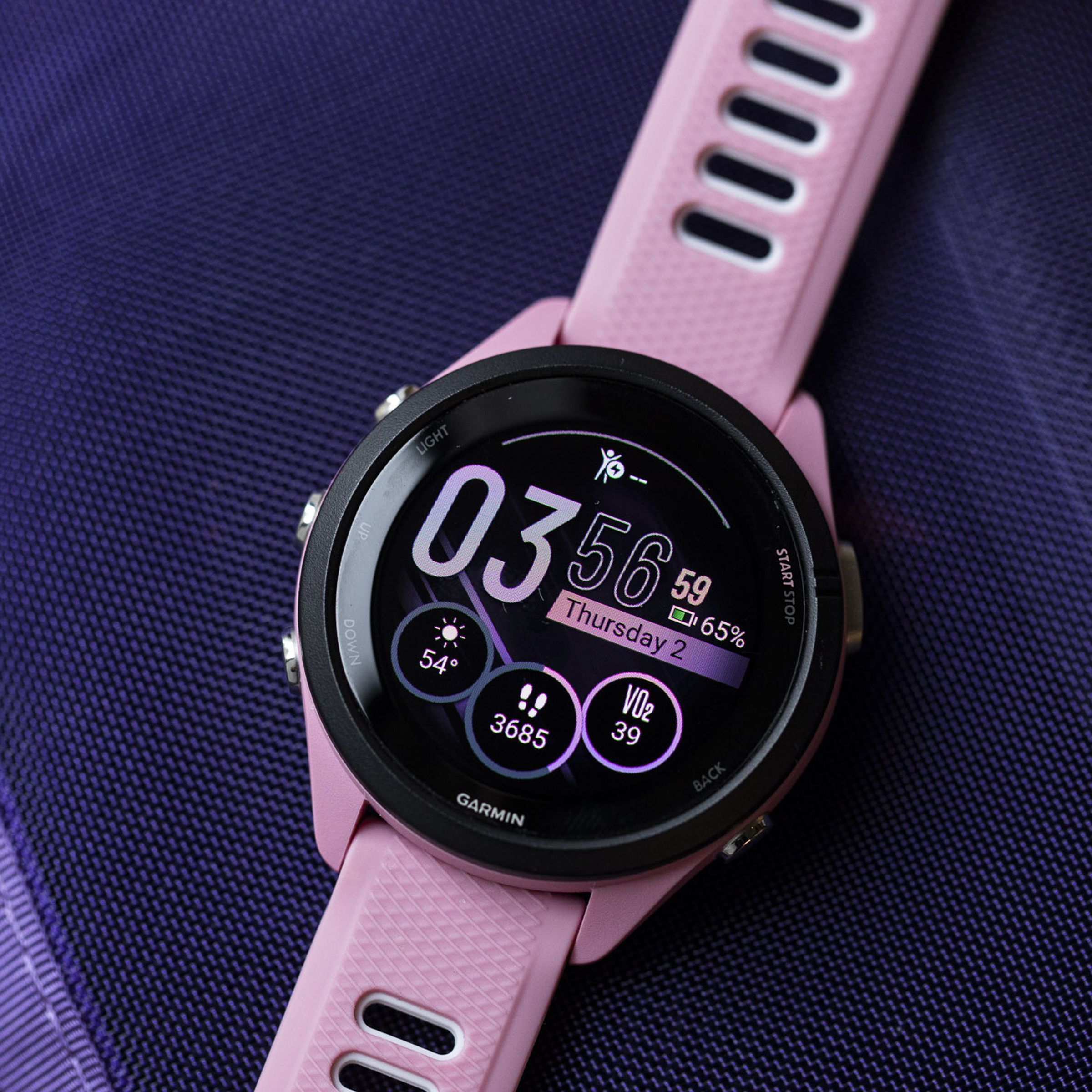 Close-up of the Garmin Forerunner 265S’s OLED display and watchface on a purple background