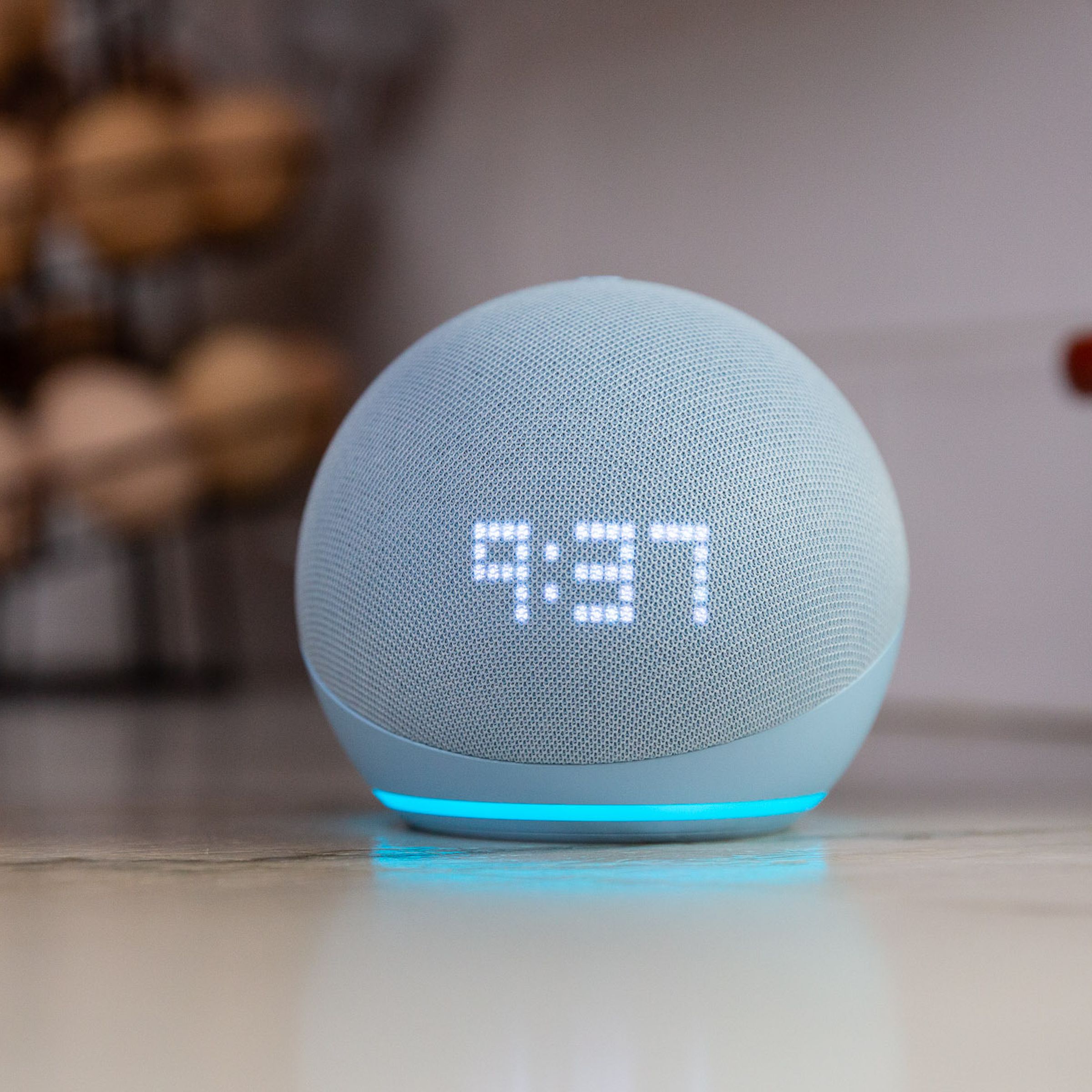 Amazon’s fifth-gen Echo Dot smart speaker showing the time on its display while sitting on a kitchen counter.