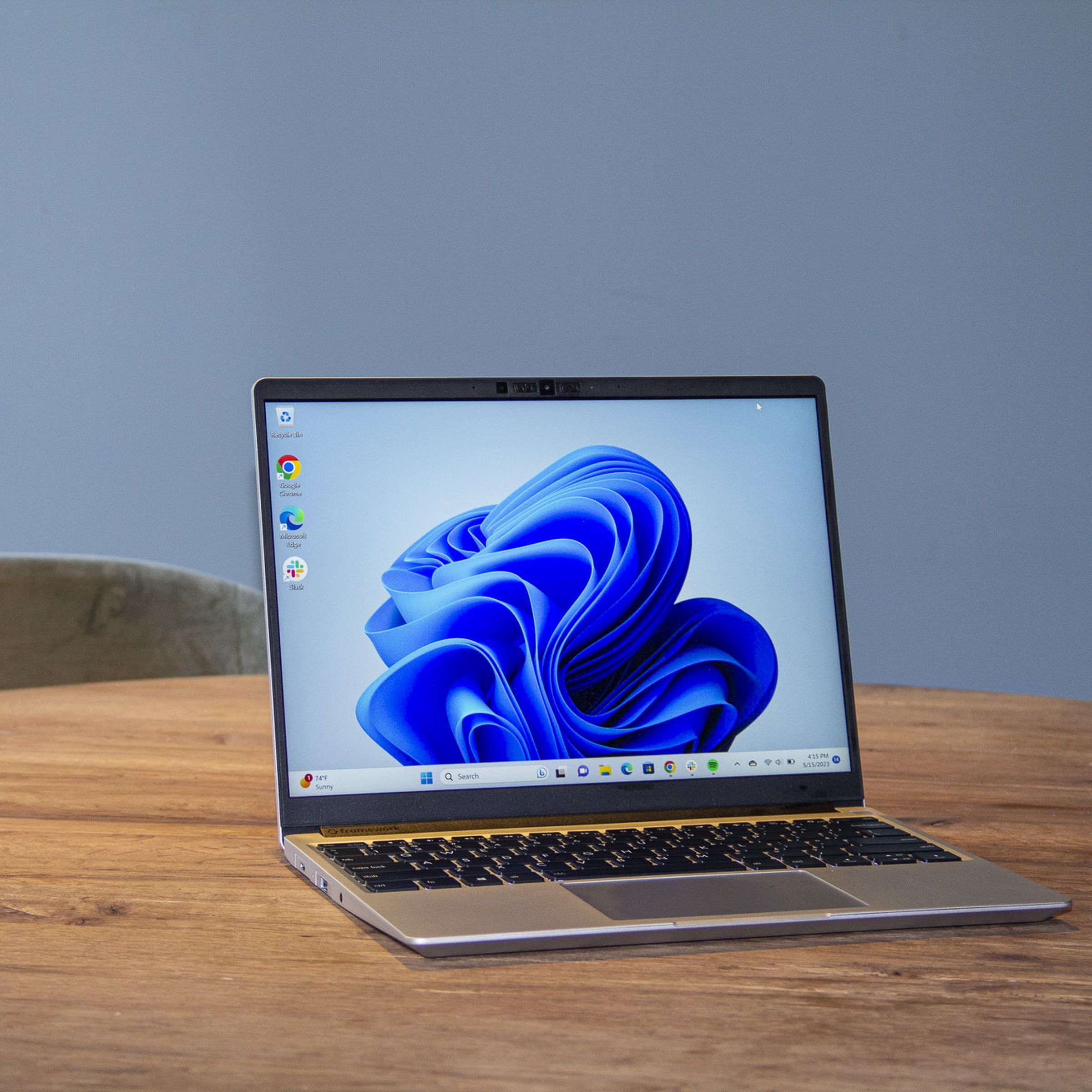 Best Laptop 2023: The Framework Laptop on a wooden table displaying a blue desktop background.