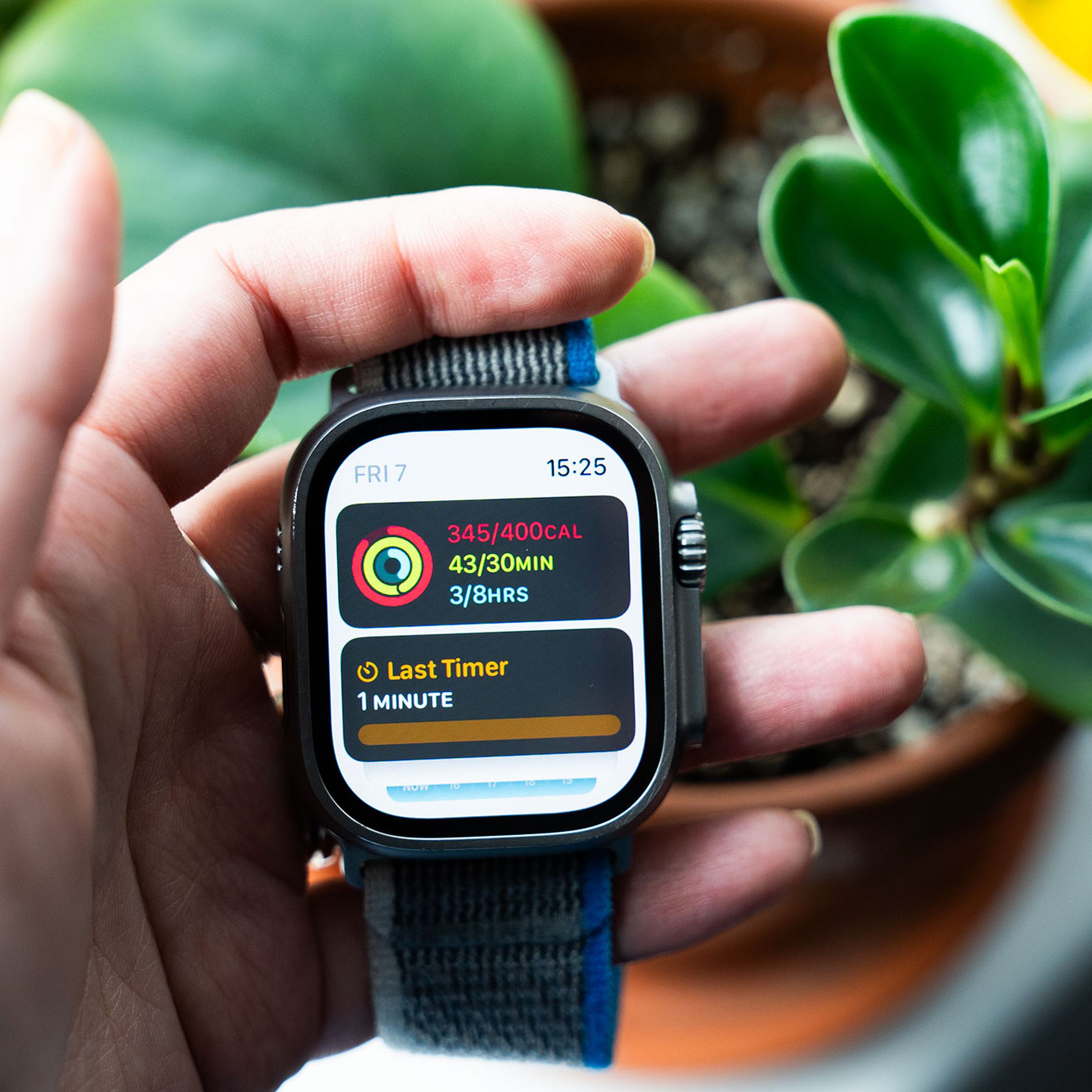 Person holding Apple Watch Ultra showing watchOS 10 widget stack