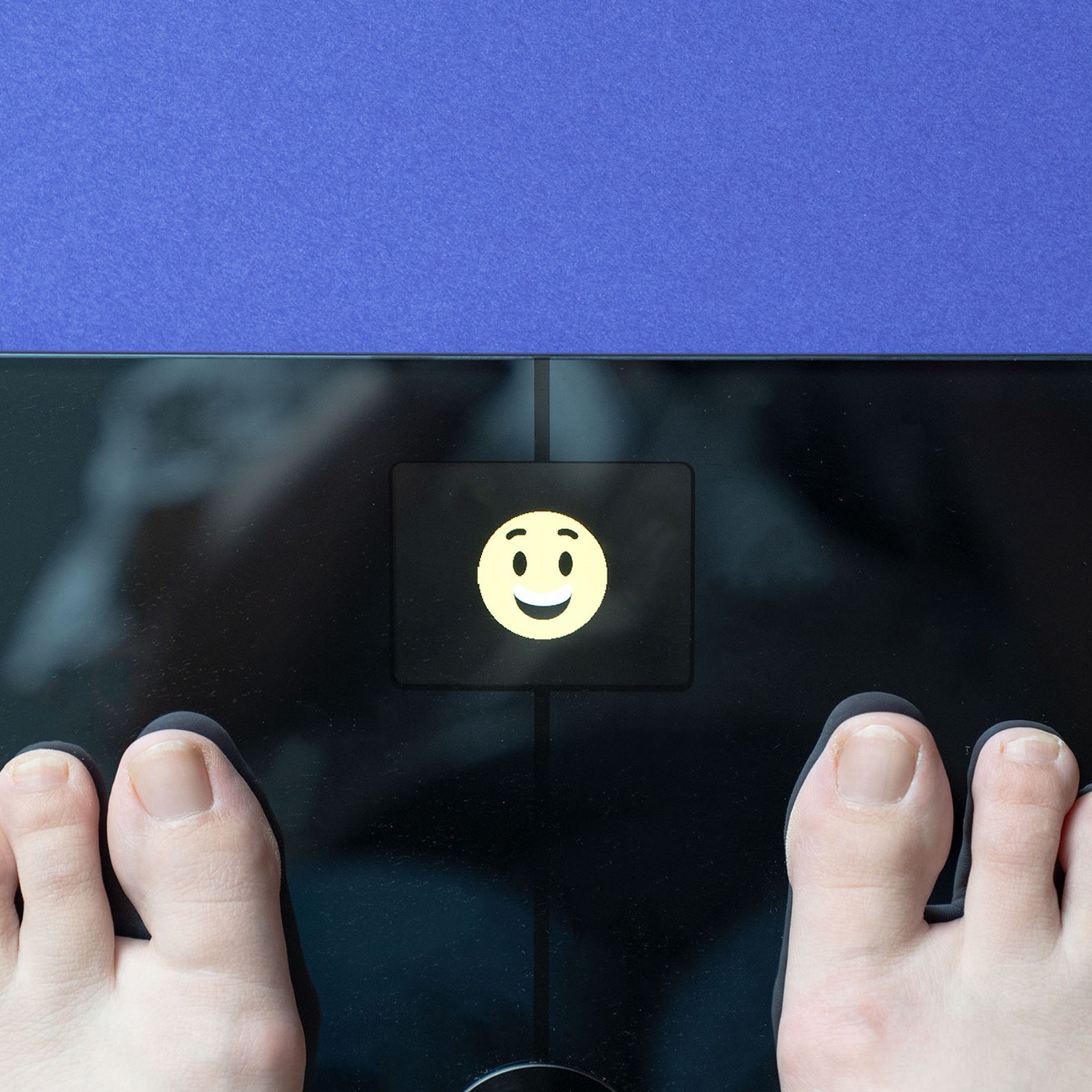 Person standing on scale with smiley face showing in LED display