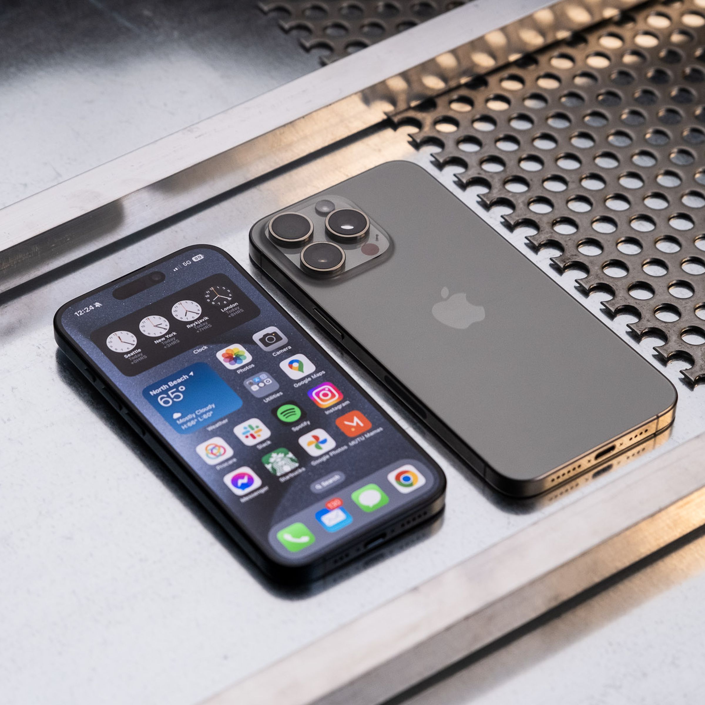 An iPhone 15 Pro and Pro Max side-by-side on a metal surface.