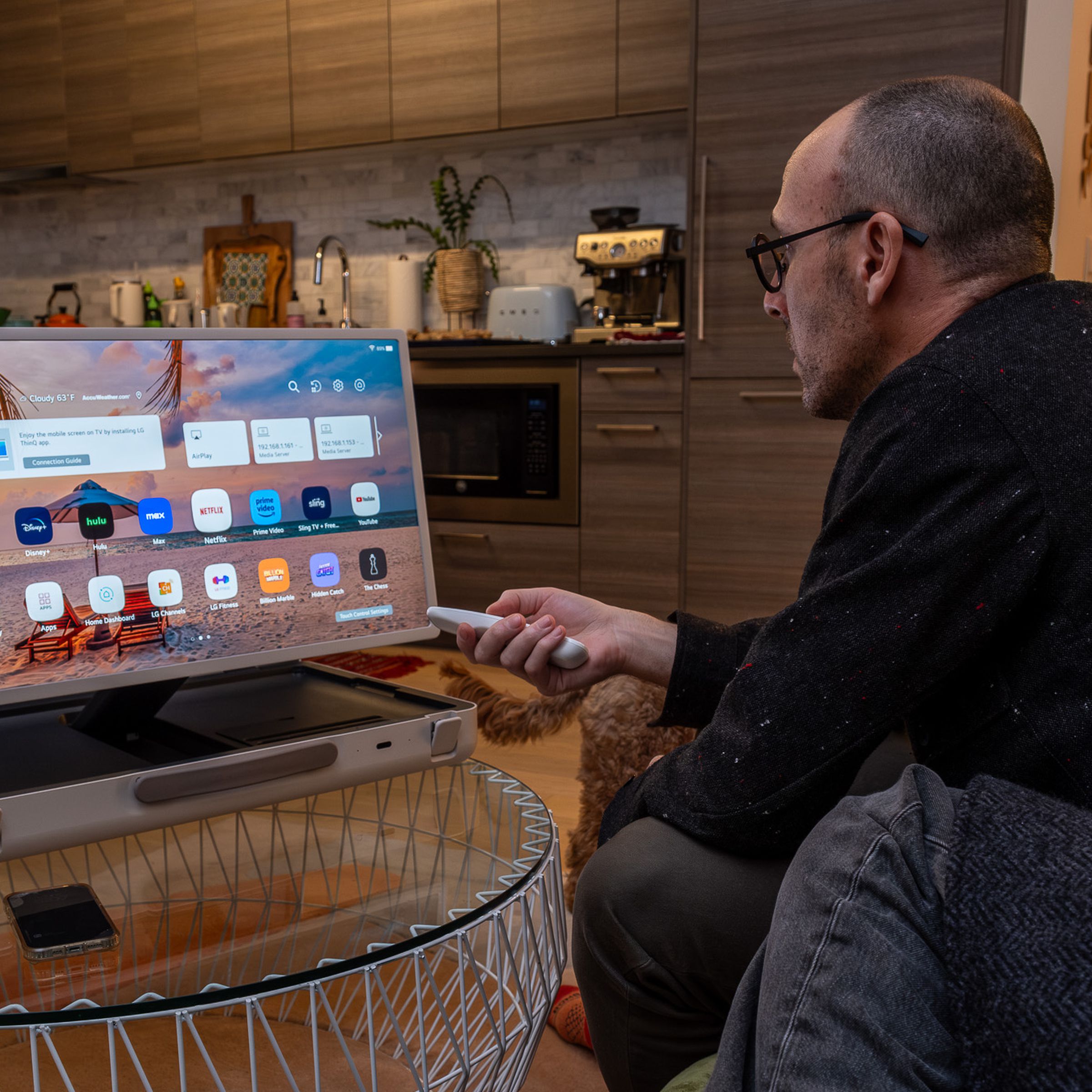 A photo of a man leaning over on a couch and using LG’s StanbyME Go briefcase TV.