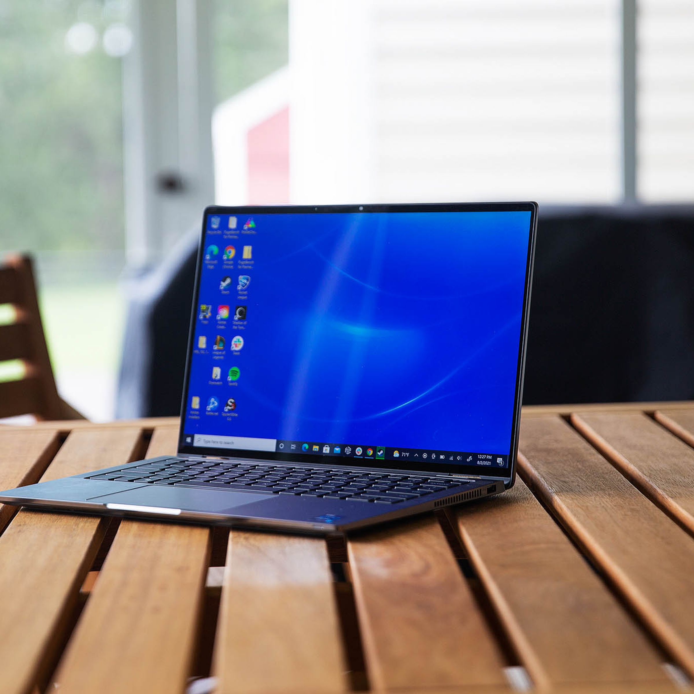 The Dell Latitude 9420 sits on a porch gable, facing to the left. The screen displays a desktop with a blue background.