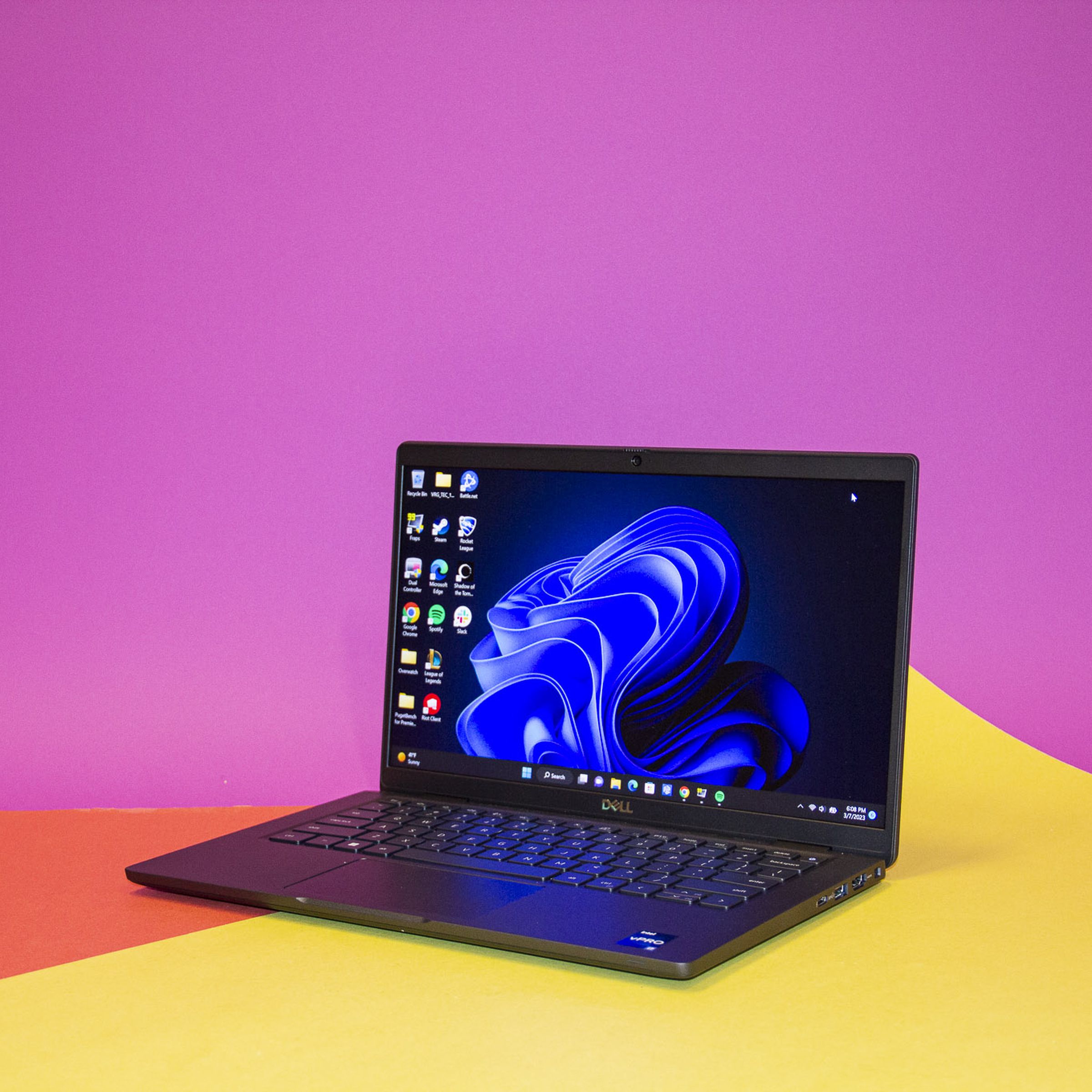 The Dell Latitude 7330 on a yellow and pink background open and angled to the left.