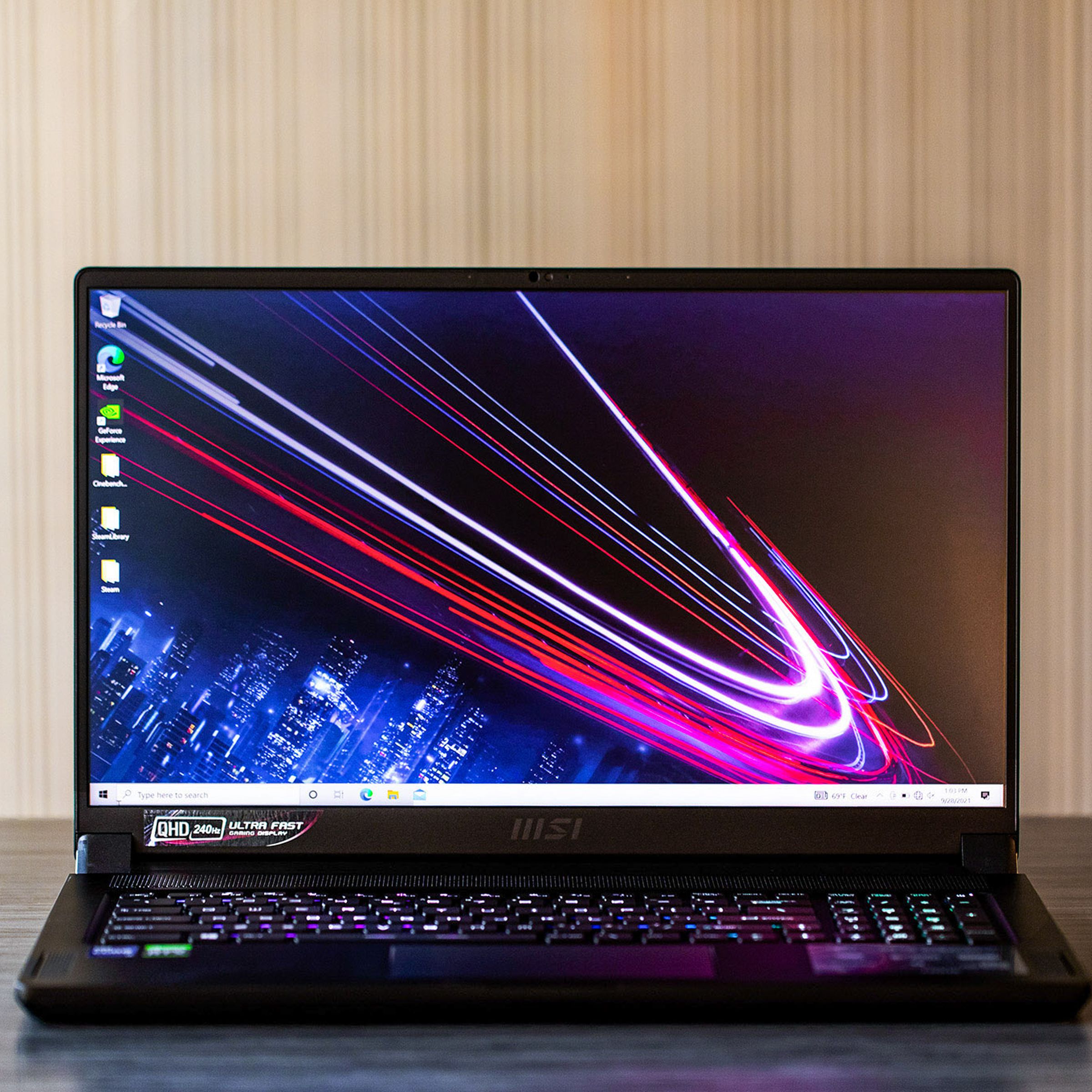 The MSI GS76 Stealth on a table, open. The screen displays a blue and dark red background.