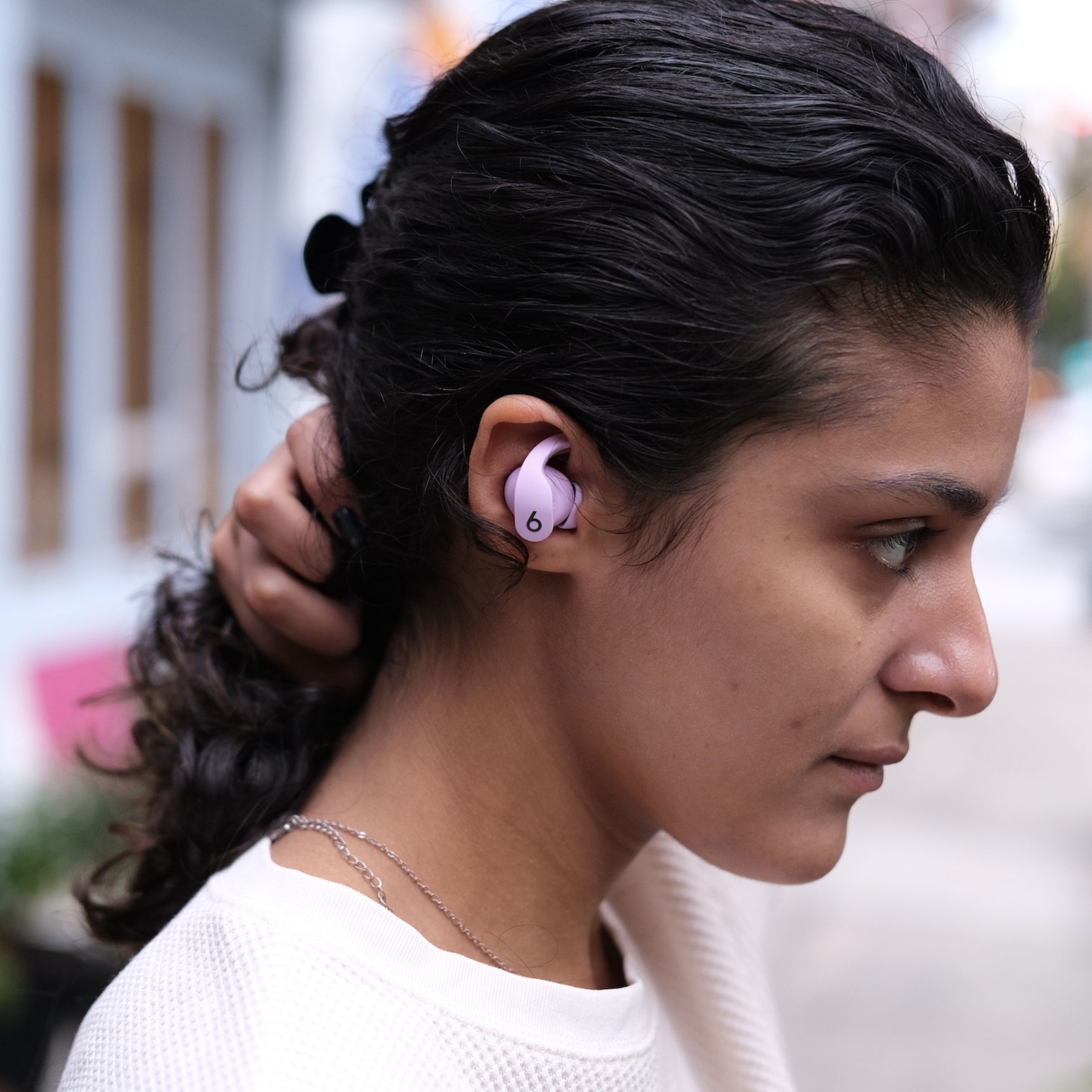 A side-profile image of the Beats Fit Pro earbuds pictured in a woman’s right ear.
