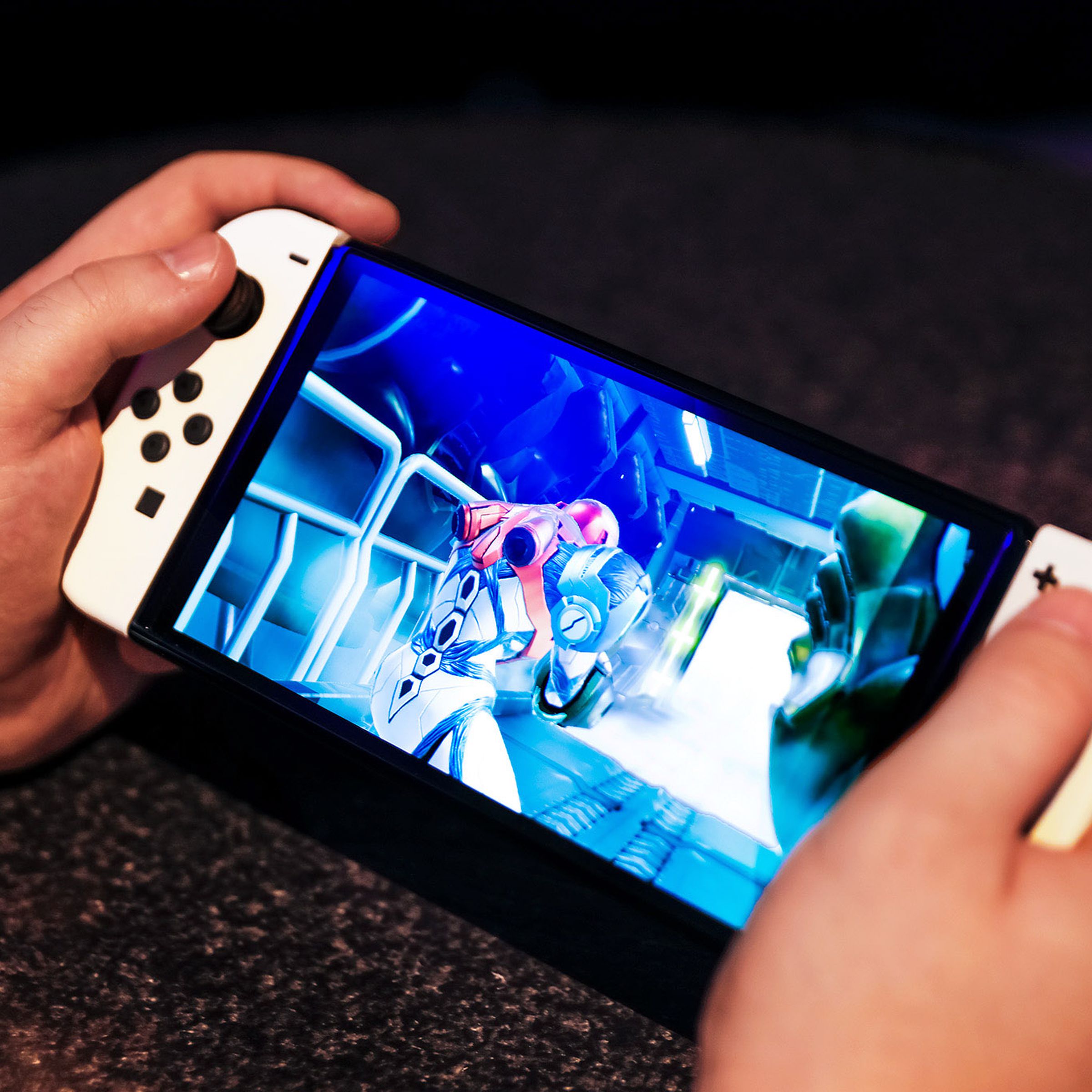 A pair of hands holding the Nintendo Switch OLED