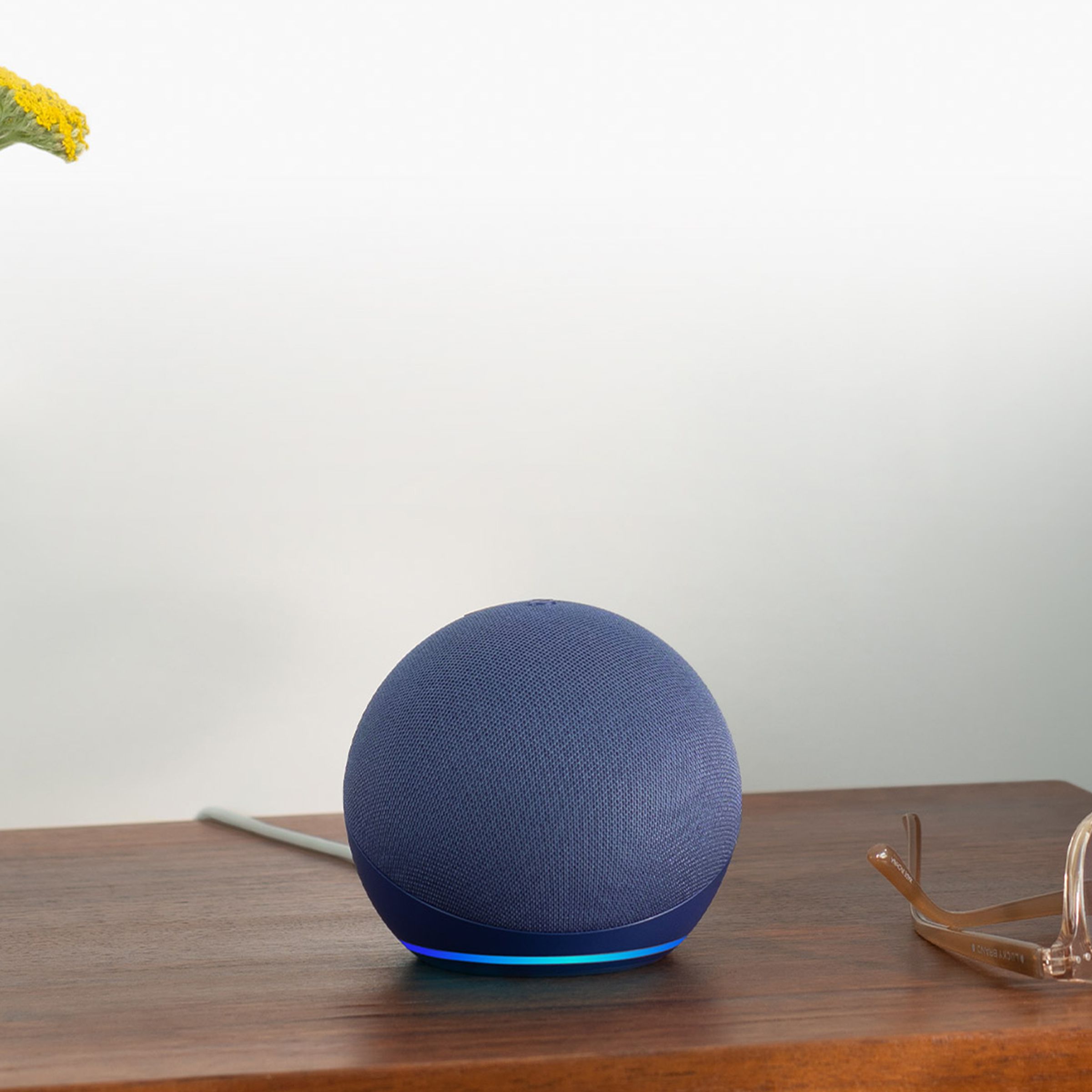 An Amazon Echo Dot (fifth-gen) in blue, resting on a side table.