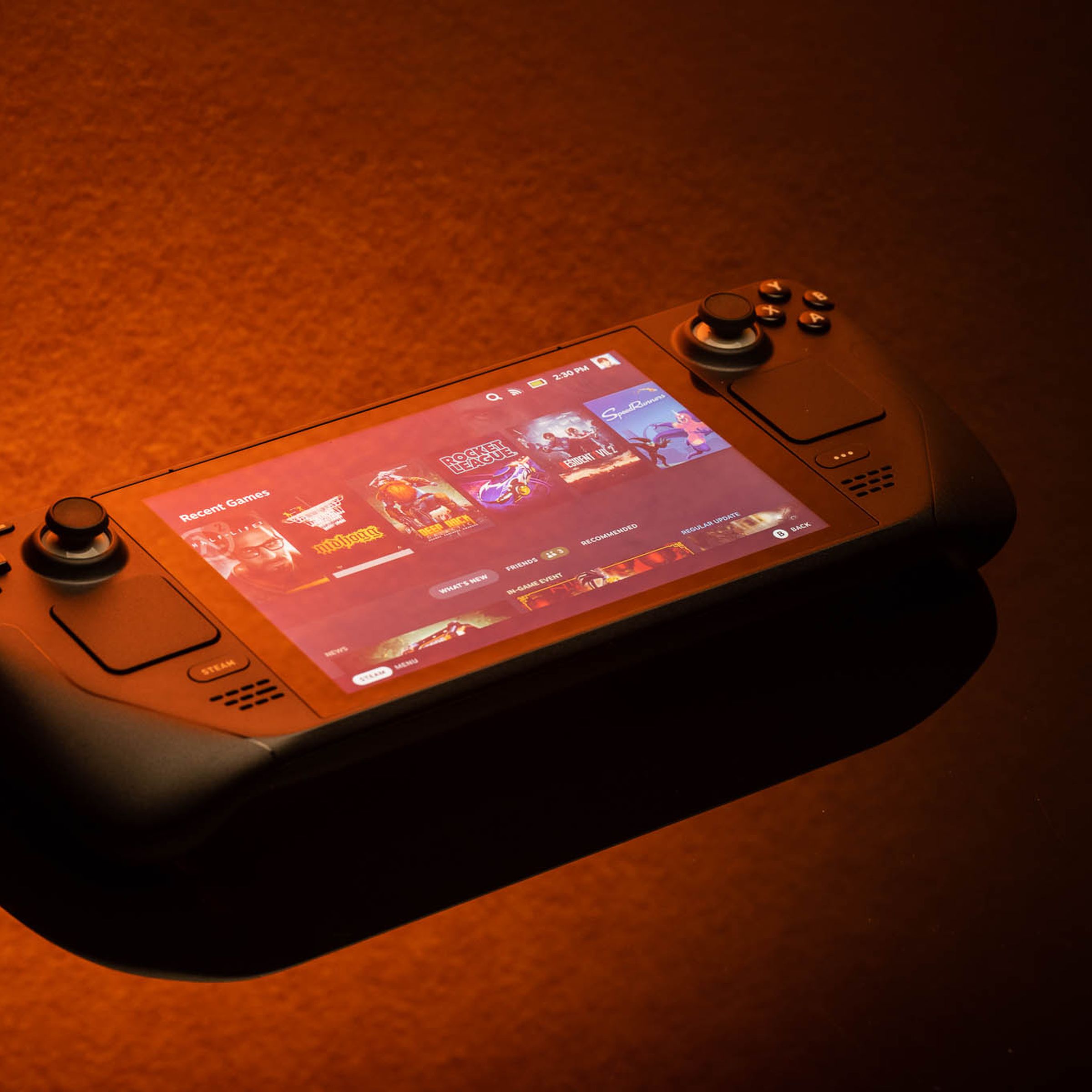 The Steam Deck gaming handheld, lit solely by orange light, giving a bit of a sunset or fire feel