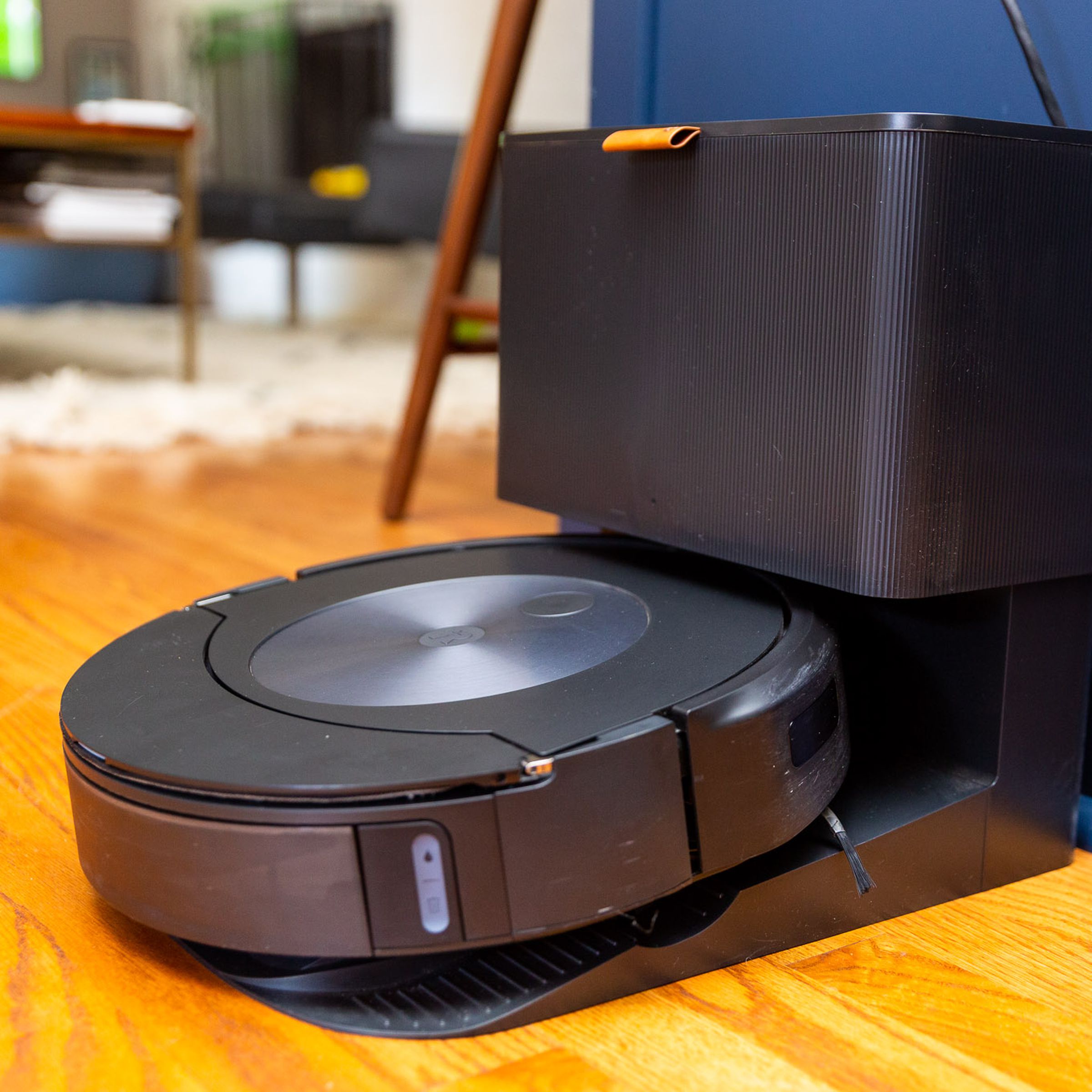 A Roomba vacuum on its docking station in an open plan kitchen living room.