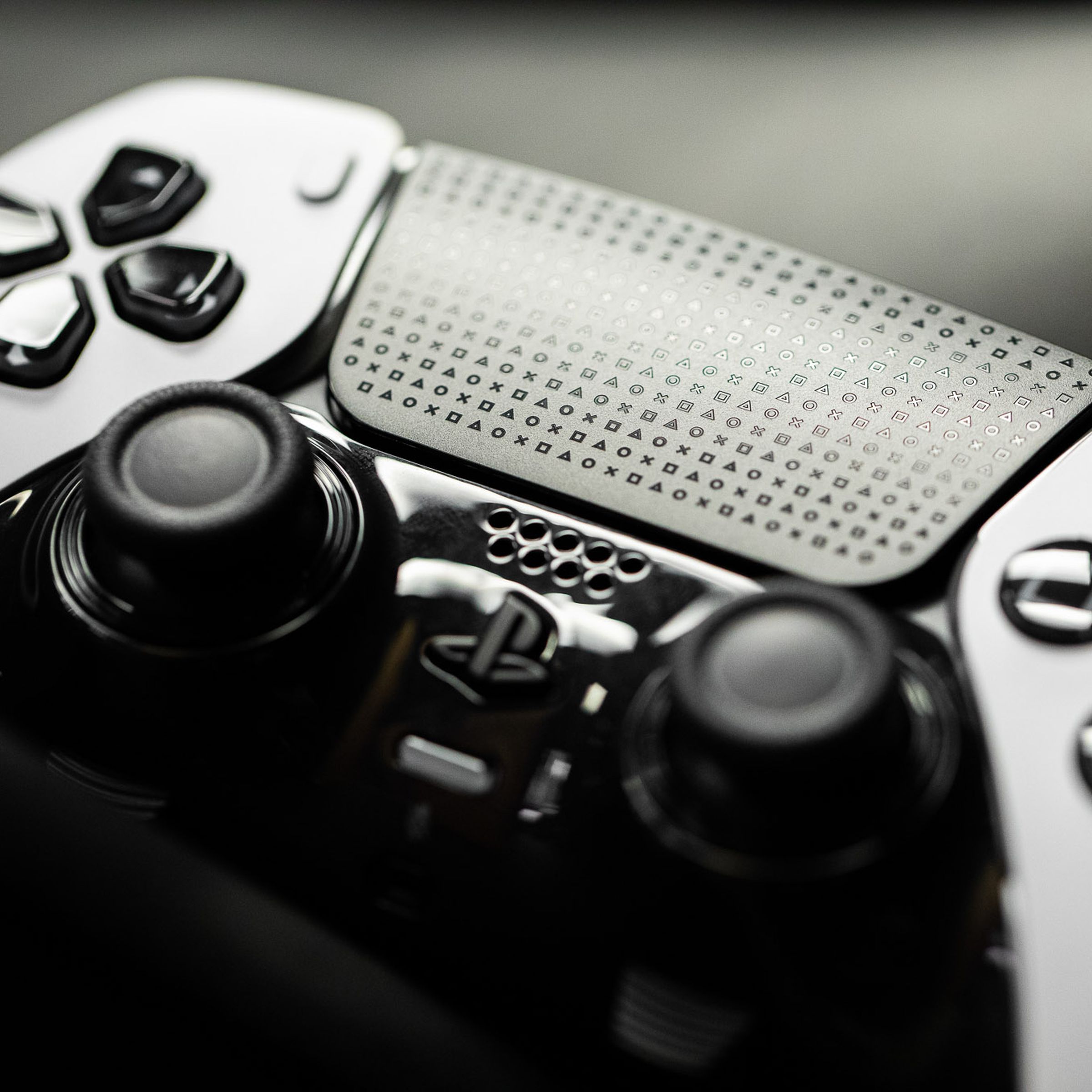 Close-up with the new premium PS5 controller, framed around its black buttons and D-pad and sticks and touchpad with PlayStation logos engraved.