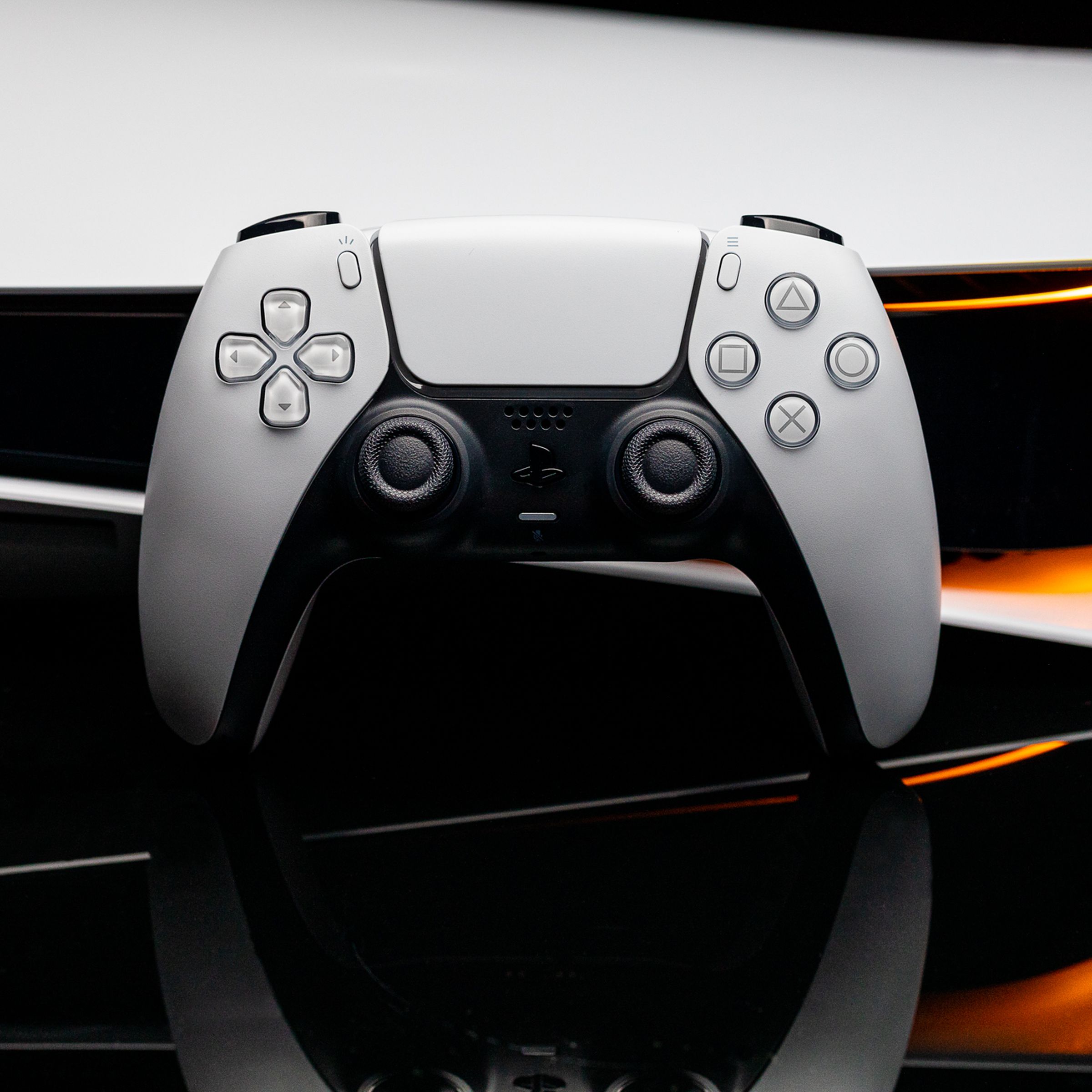 Orijinal bir PlayStation 5'in önündeki PlayStation DualSense denetleyicisinin görüntüsü.