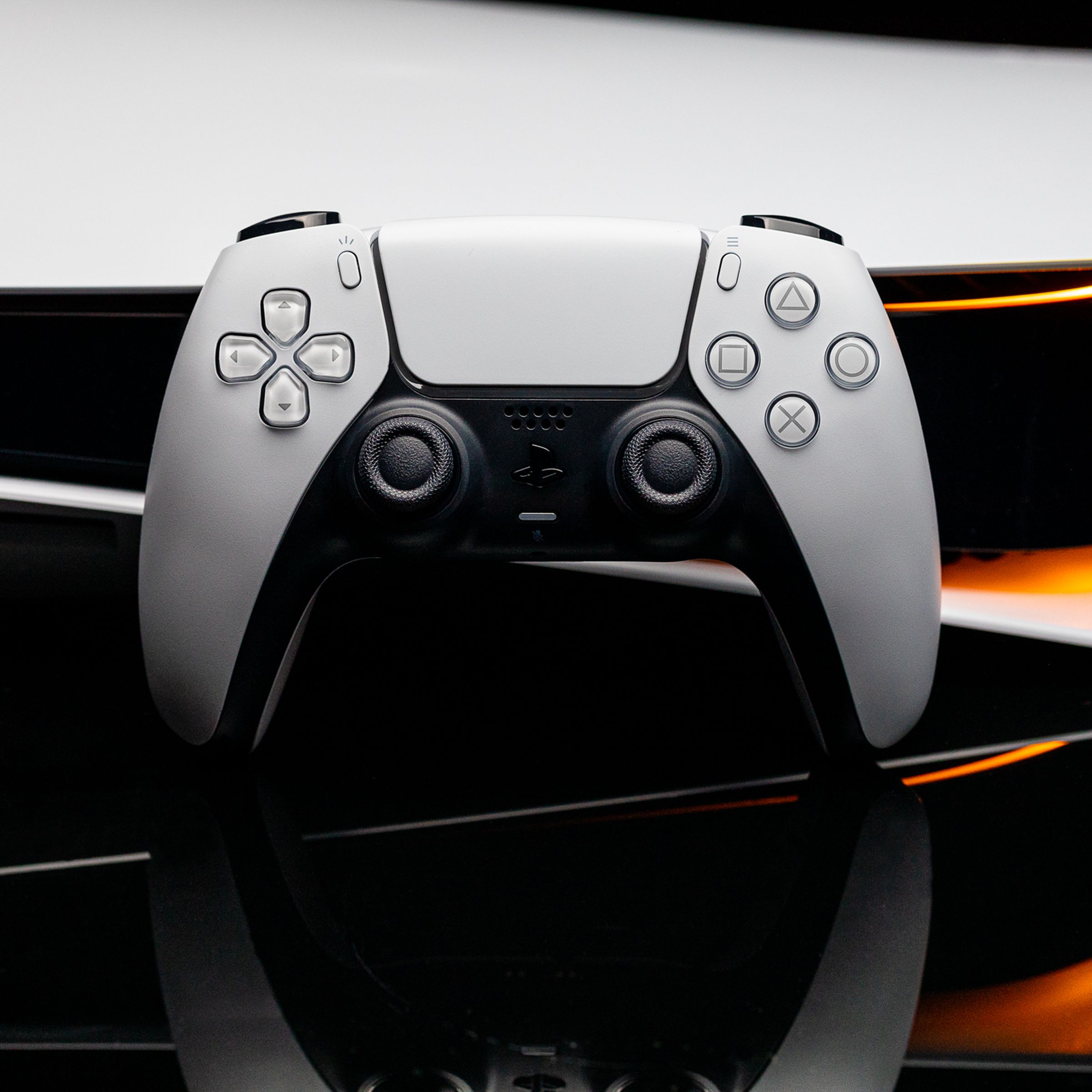 Image of a PlayStation DualSense controller in front of an original PlayStation 5.