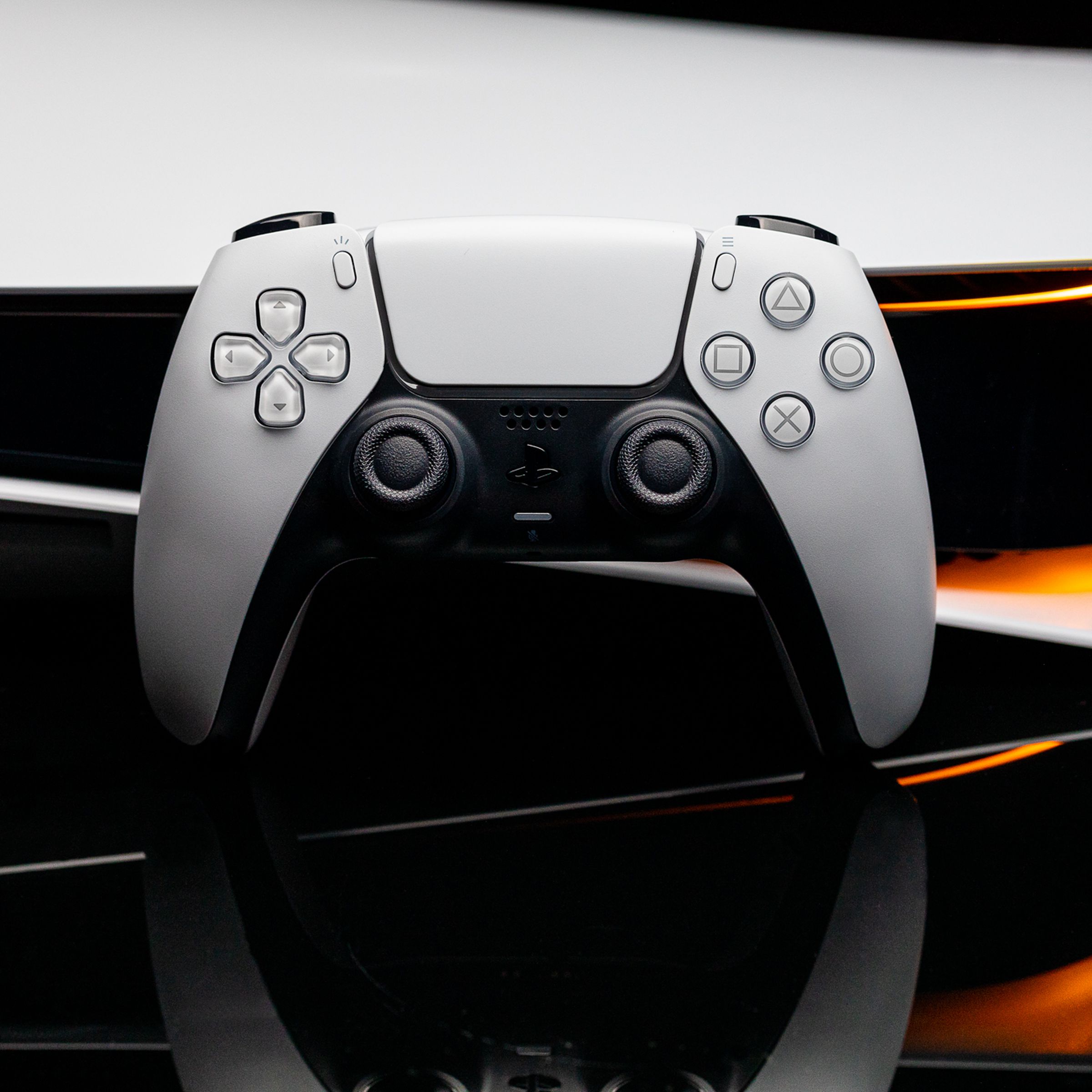 Image of a PlayStation DualSense controller in front of an original PlayStation 5.