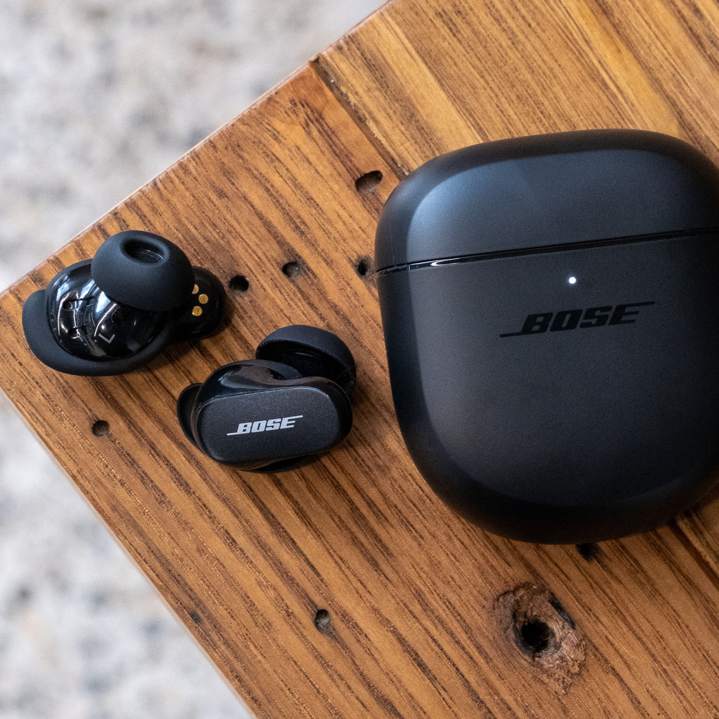 An overhead image of Bose QuietComfort Earbuds II on a wooden table.