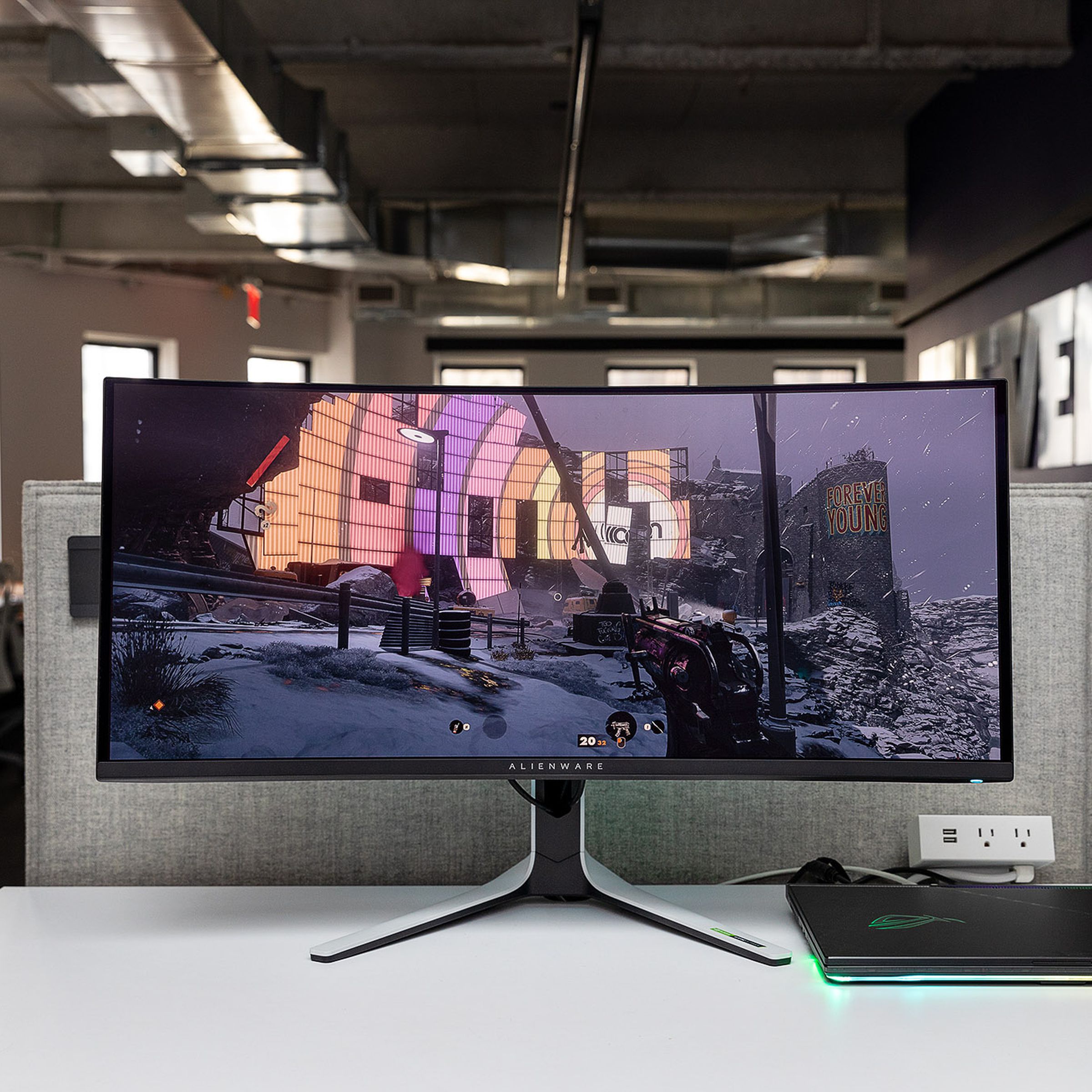 Alienware QD-OLED gaming monitor sitting on a white desk in a well-lit room displaying the game Deathloop.