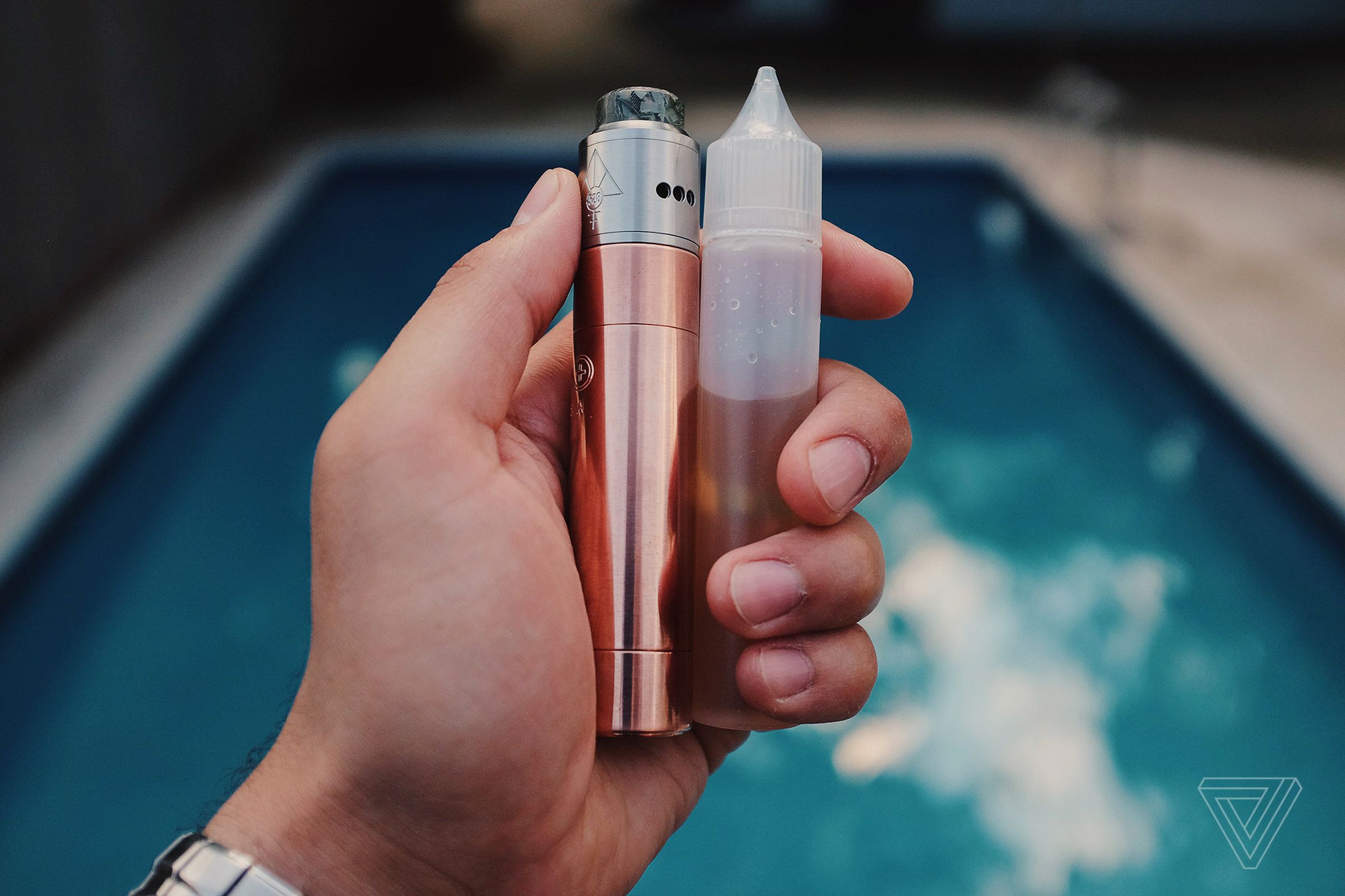 A mechanical tube mod with a rebuildable dripping atomizer and a bottle of vape juice.